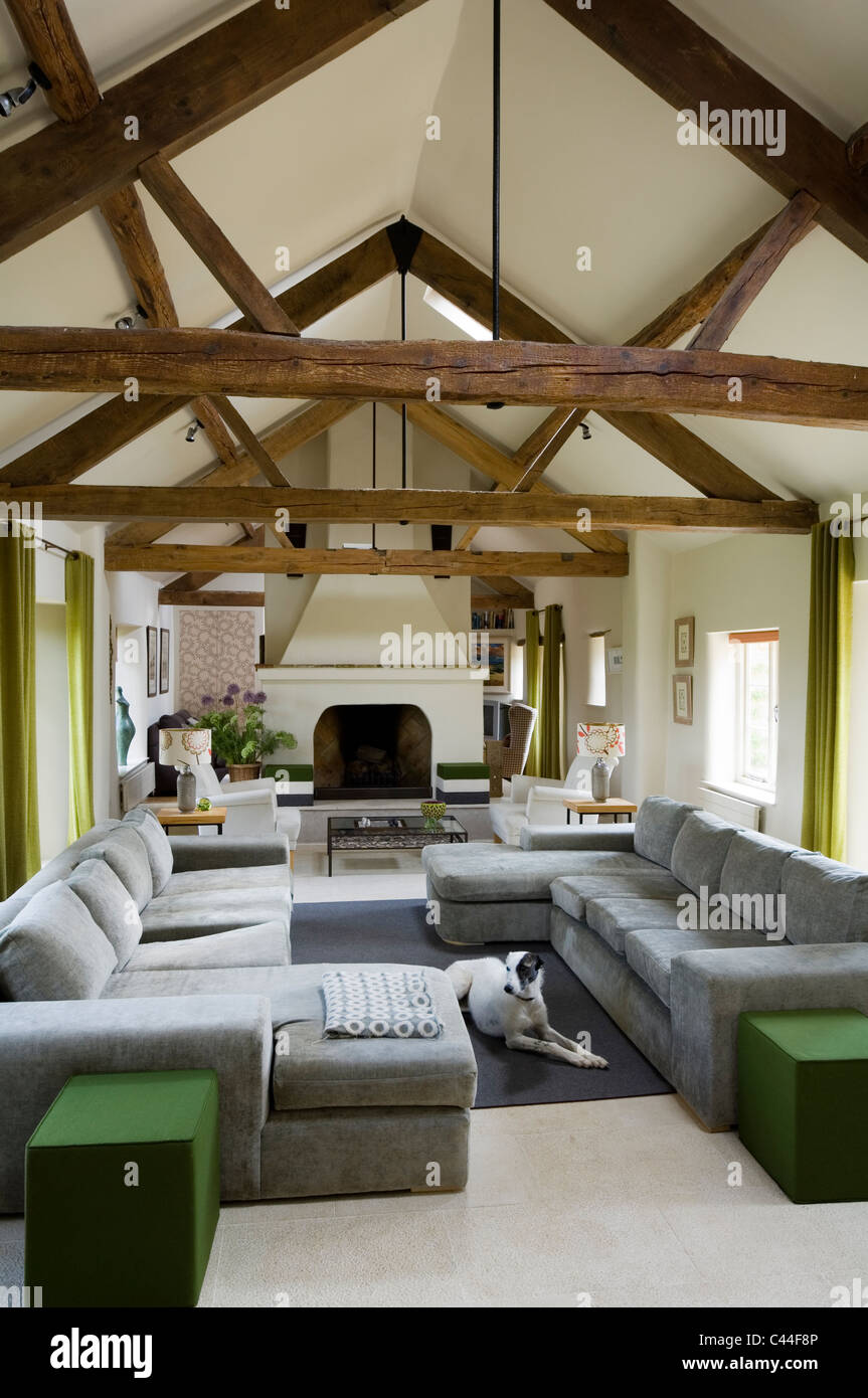 Öffnen Sie Plan umgebaute Scheune mit Holzbalken an den Decken, graue Sofas und offenem Kamin Stockfoto