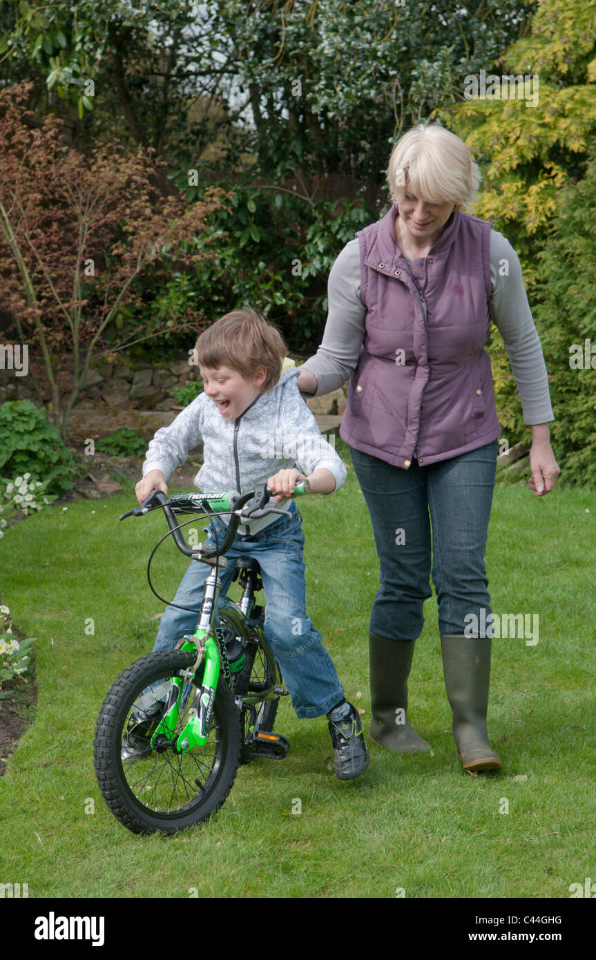 Großmutter Enkel, mit dem Fahrrad in einem Garten hinter dem Haus Unterricht Stockfoto