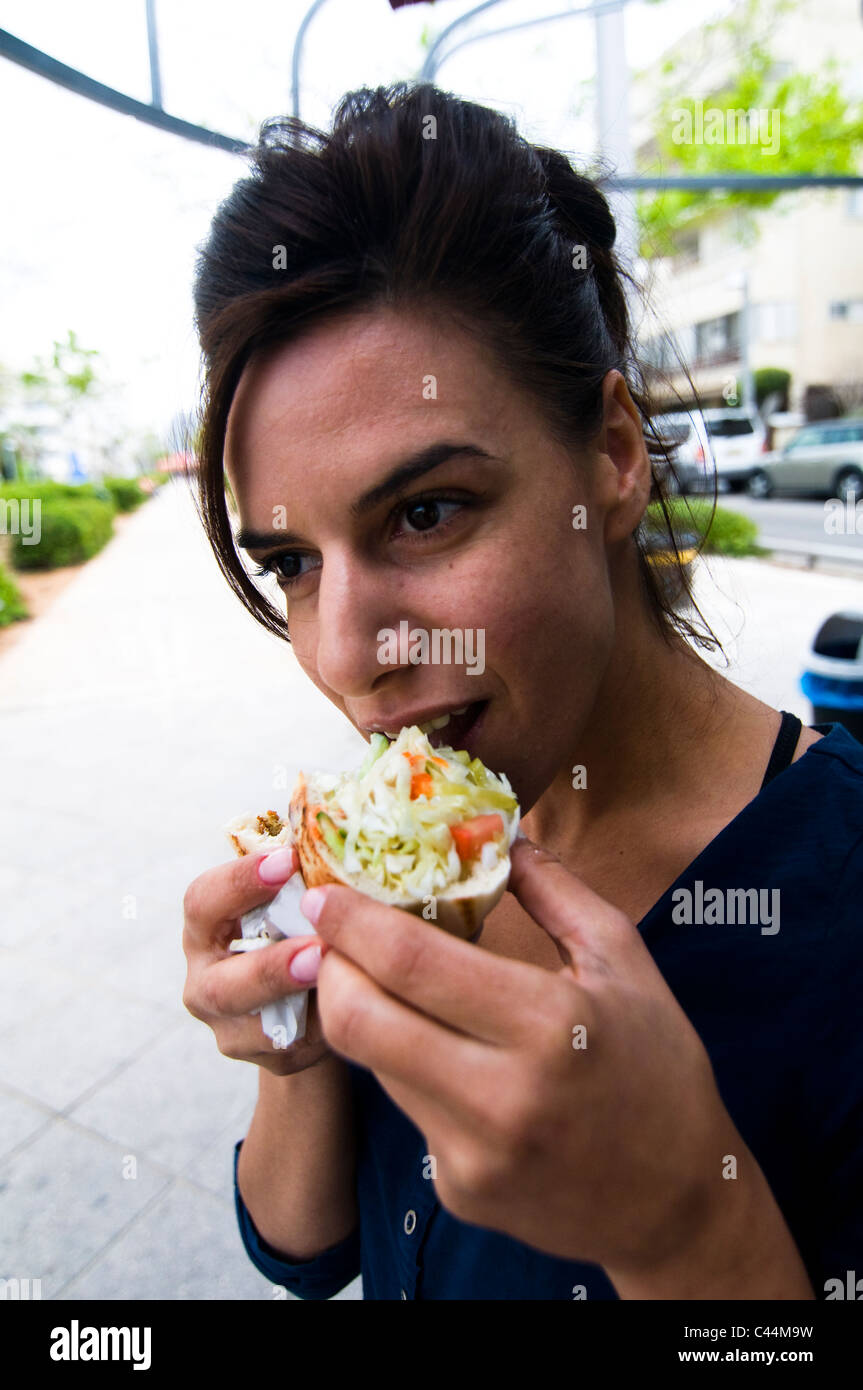 Eine israelische Schönheit genießt A Falafel in Fladenbrot Sandwich. Stockfoto