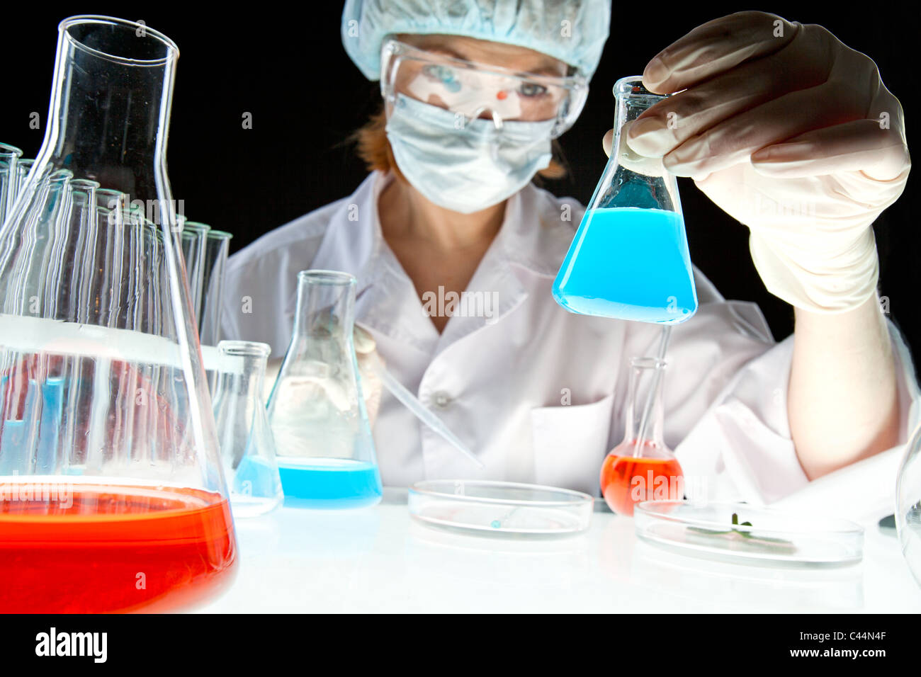Labor-Arbeiter, die Flasche mit Flüssigkeit während der Experimente im Labor zu betrachten Stockfoto