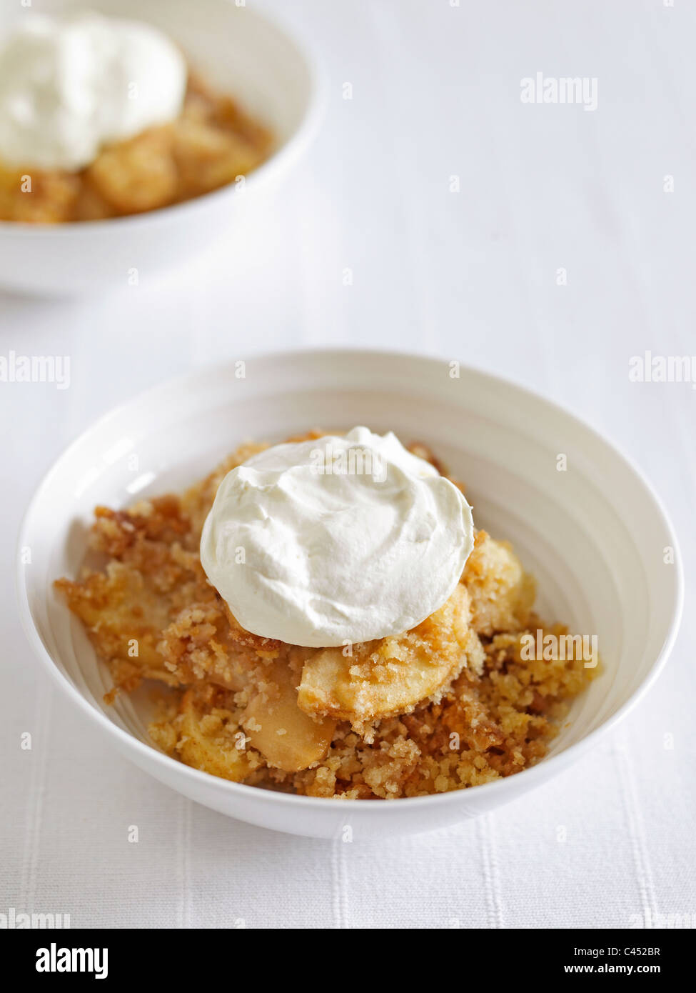 Schüssel mit Apple Brown Betty mit Sahne, Nahaufnahme Stockfoto