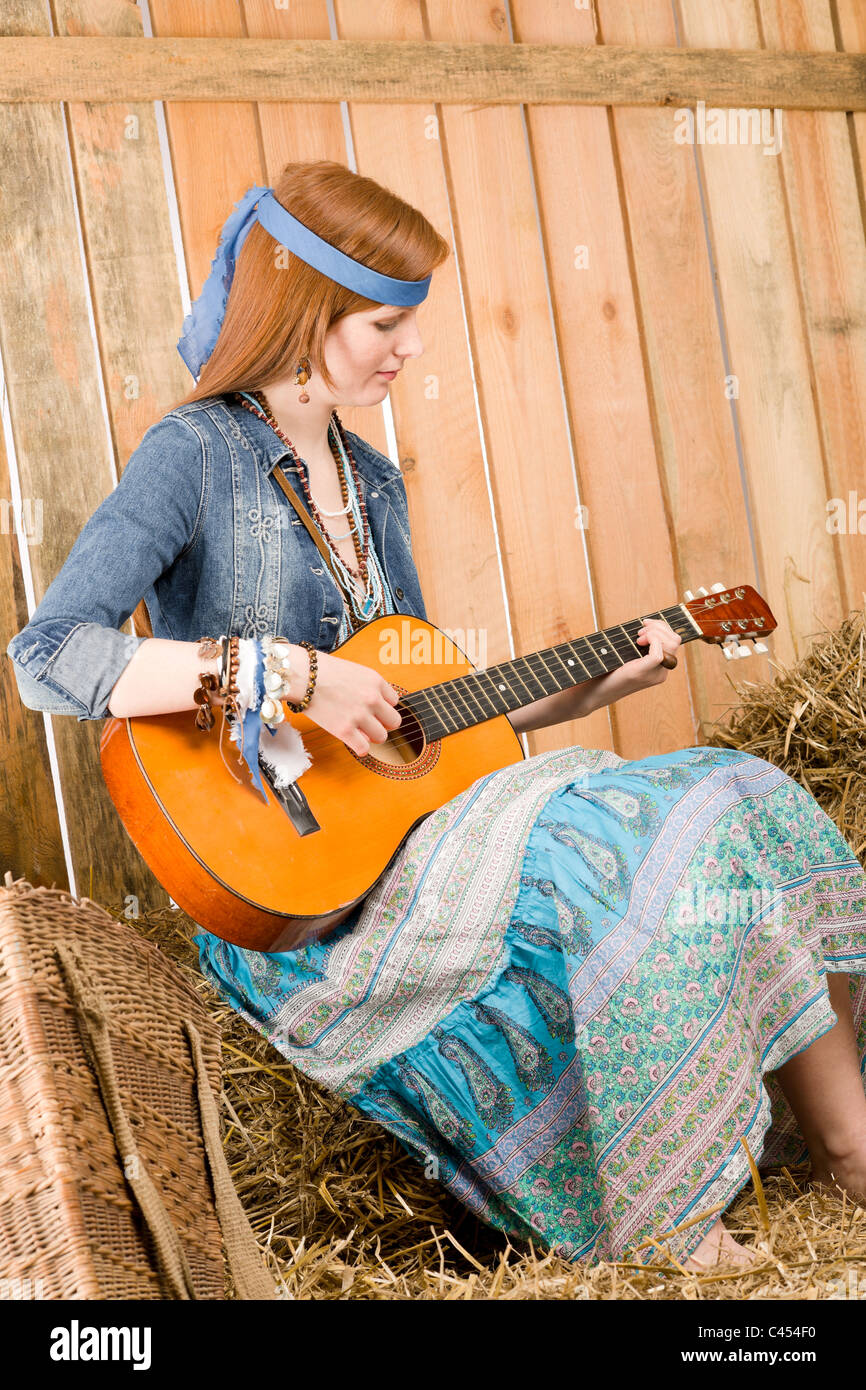 Jungen Hippie-Frau spielen Gitarre sitzen auf Heu in der Scheune Stockfoto