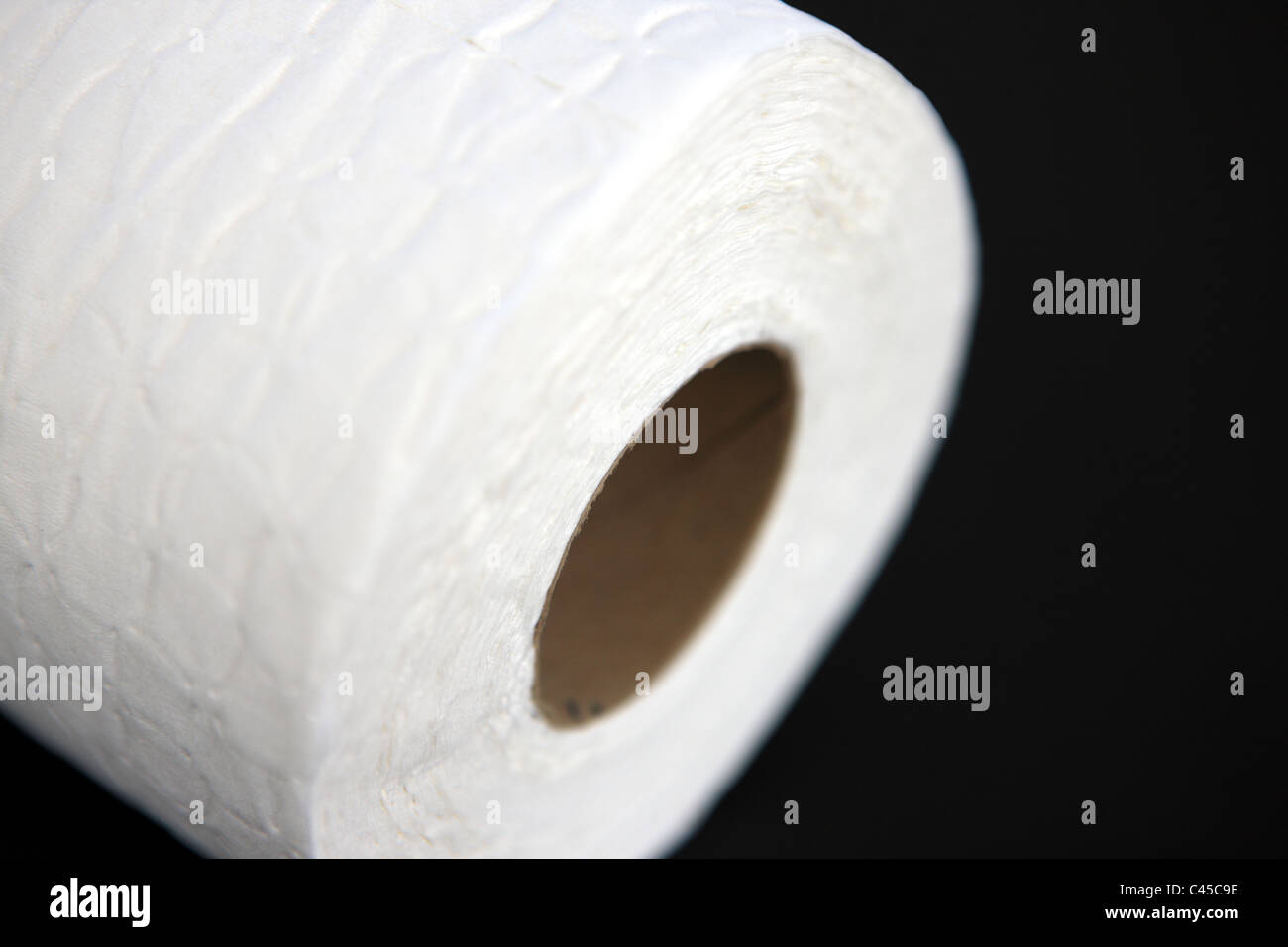 WC-Papierrolle vor schwarzem Hintergrund Stockfoto