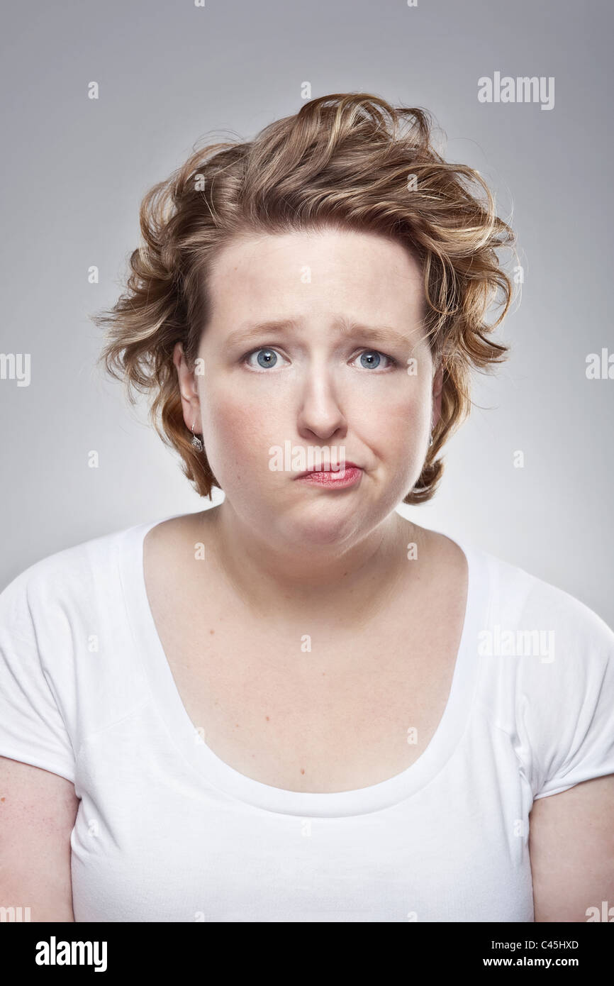 Ein Studio-Porträt einer schrulligen übergewichtigen jungen Frau haben einen schlechten Tag. Sie hat einen niedergeschlagenen aber humorvollen Ausdruck. Stockfoto