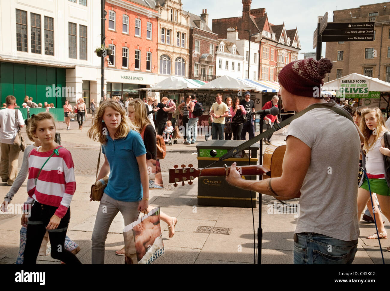 Menschen beobachten ein Straßenmusikant Gesang mit Gitarre, dem Marktplatz, Cambridge UK Stockfoto