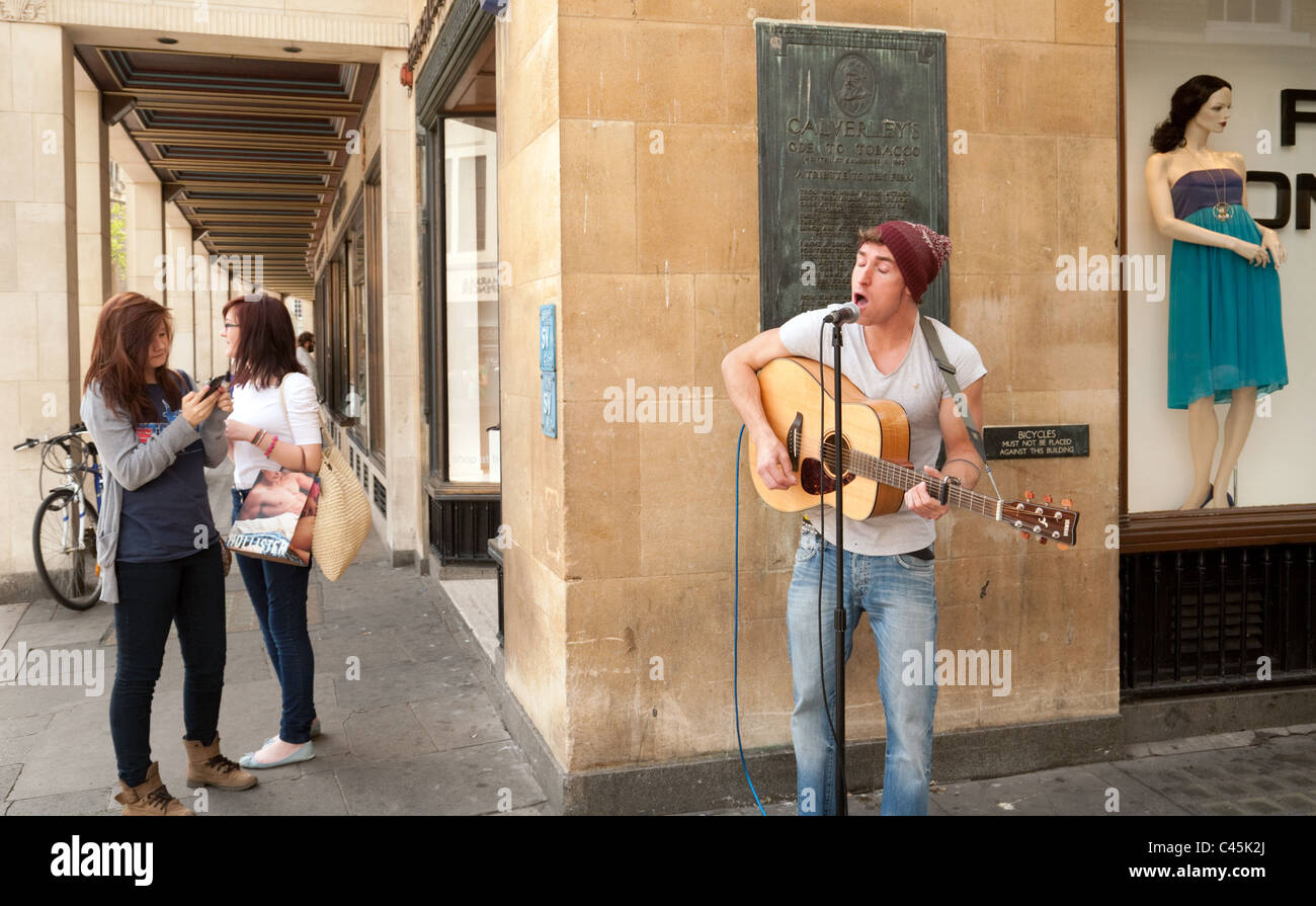 Menschen beobachten ein Straßenmusikant Gesang mit Gitarre, dem Marktplatz, Cambridge UK Stockfoto