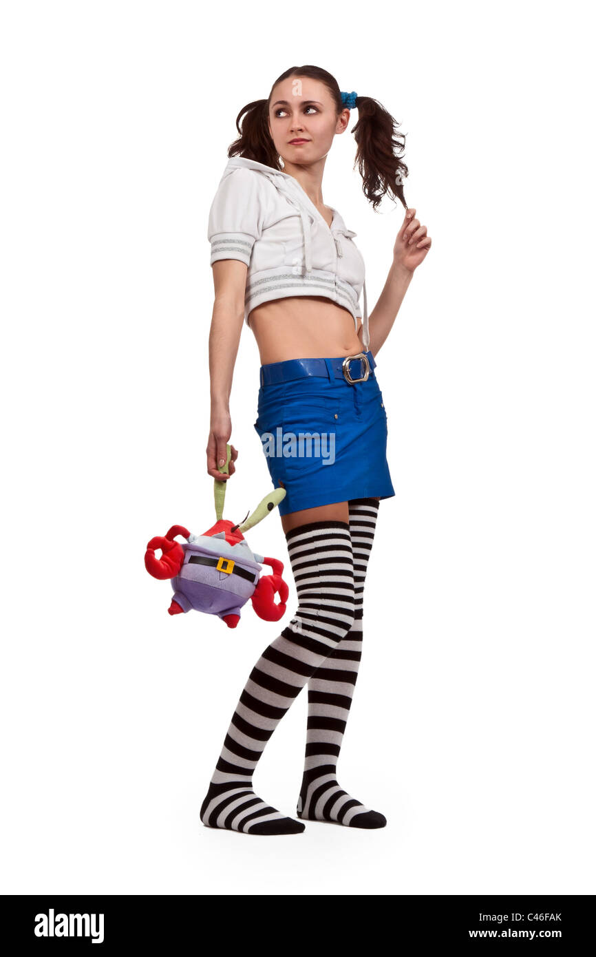 Mädchen in gestreiften Socken, Minirock mit Spielzeug und Zöpfen Stockfoto