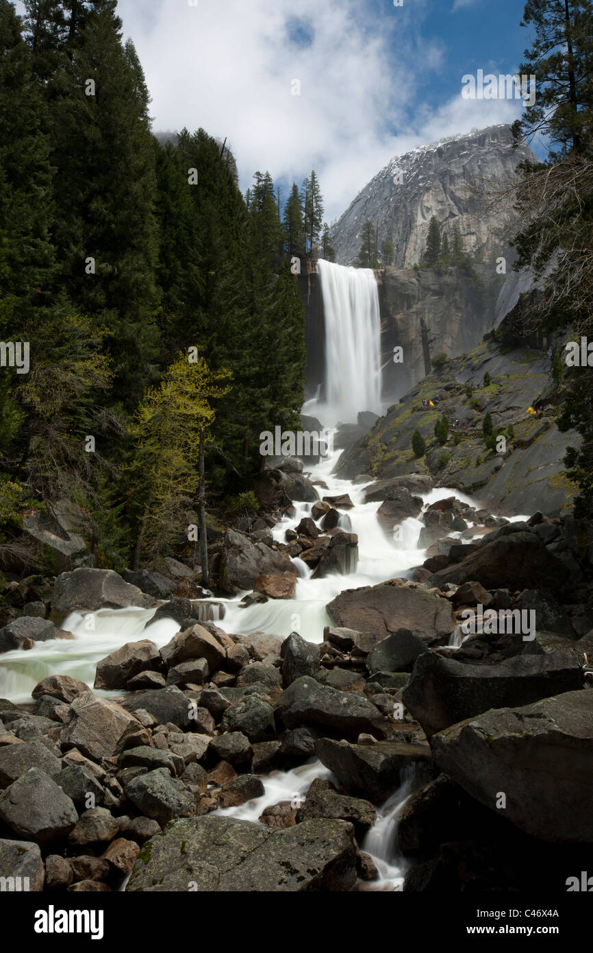 Vernal Falls Wasserfälle hoher Wasserdurchfluss Frühjahr die Schneeschmelze über Geröll Yosemite National Park uns blauer Himmel, grüne Bäume kreative Zeitraffer winzige Menschen Stockfoto