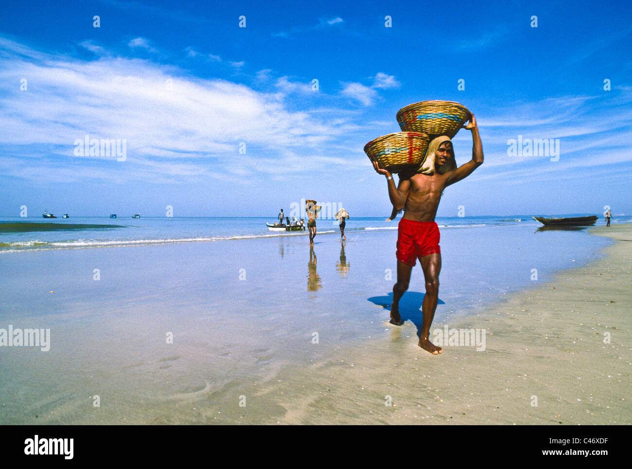 Entladung Körbe mit Fischen vom Boot auf Calva Strand in Goa, Indien Stockfoto