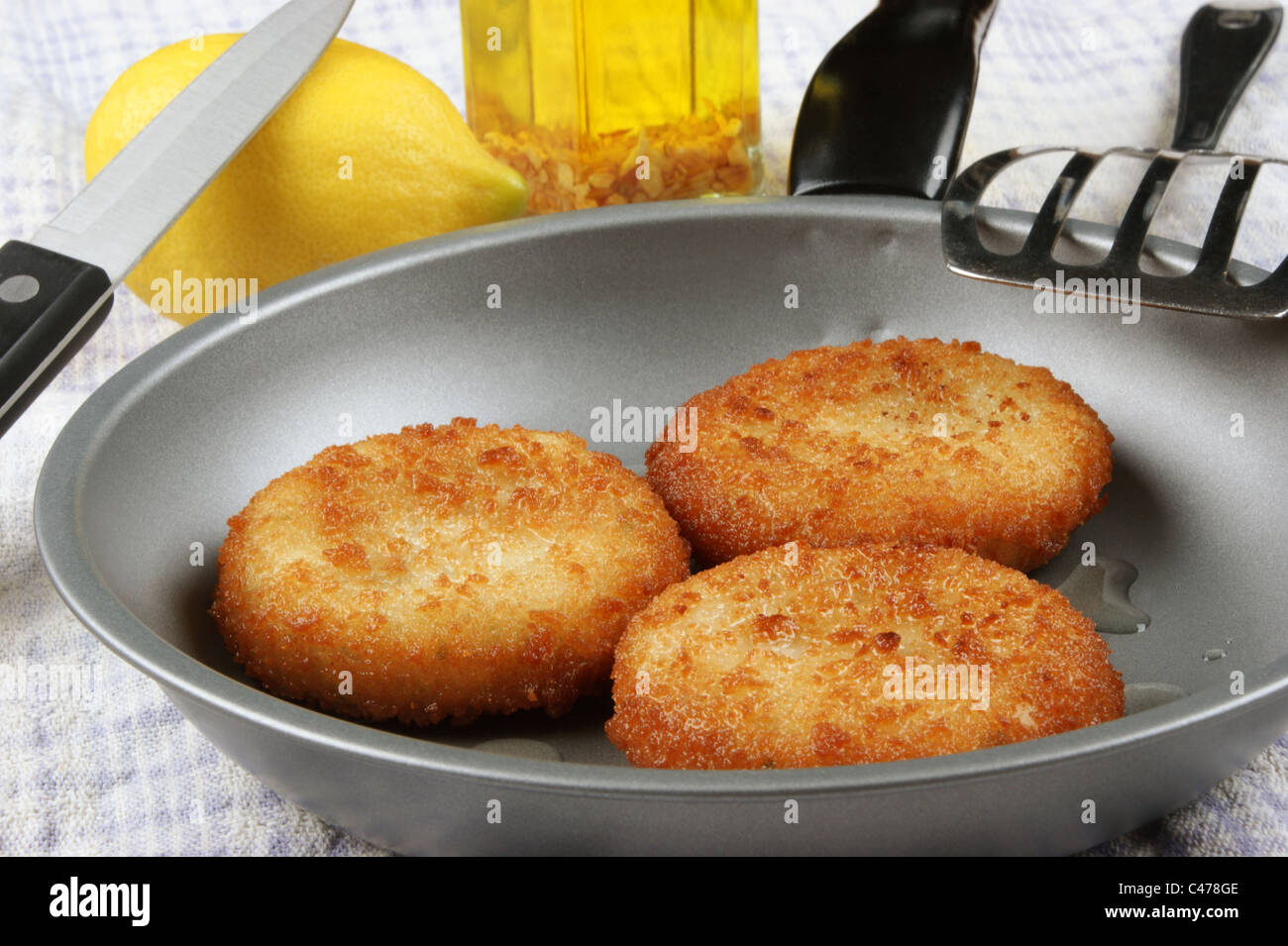 drei frisch gebratenen Fisch Kuchen in einer Pfanne Stockfoto