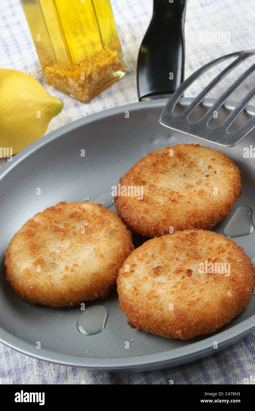 drei frisch gebratenen Fisch Kuchen in einer Pfanne Stockfoto