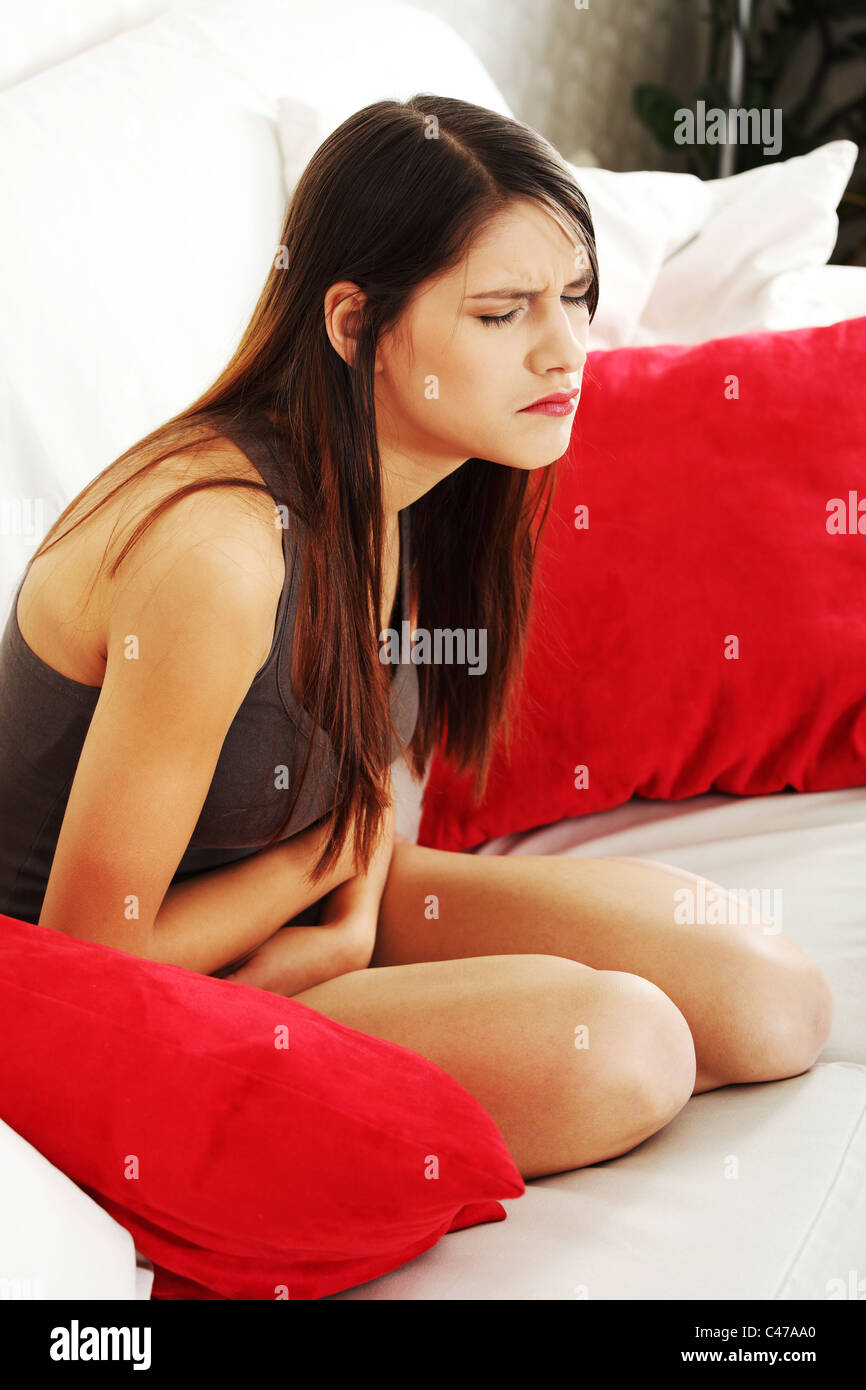 Frau mit Magenschmerzen auf Sofa in ihrem Haus Stockfoto