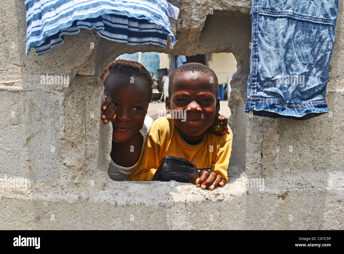Kinder spähen durch Loch in einer Wand in Abidjan, Elfenbeinküste, Westafrika Stockfoto