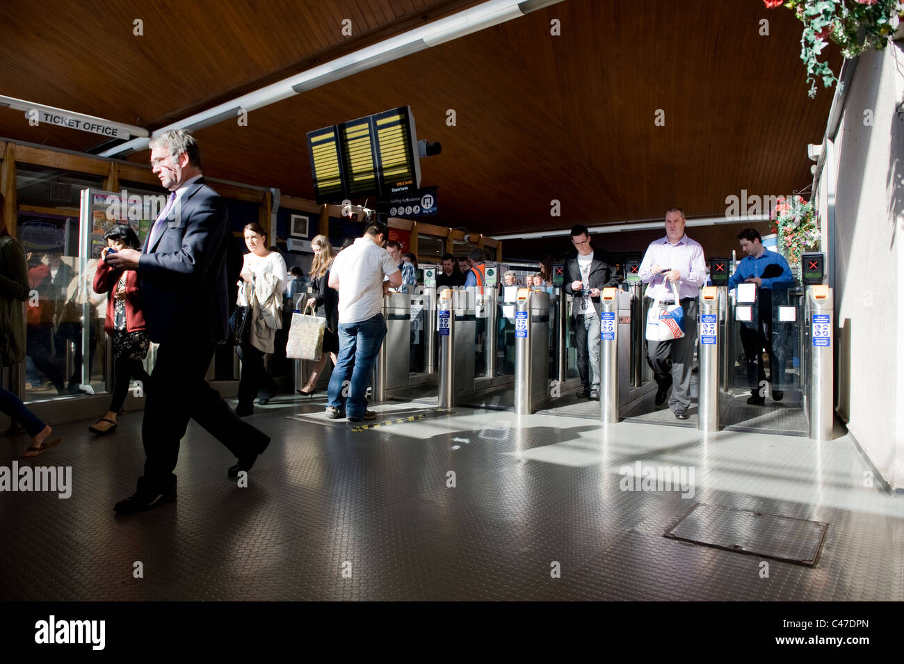 Pendler durchlaufen eine Ticket-Barriere an einem sonnigen Morgen am Bahnhof in Manchester Oxford Road. Stockfoto