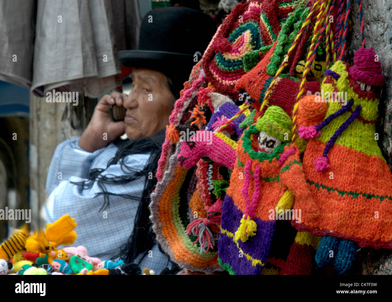 Eine bolivianische Frau auf einem Markt in Tracht gekleidet und mit Hilfe eines Mobiltelefons Stockfoto