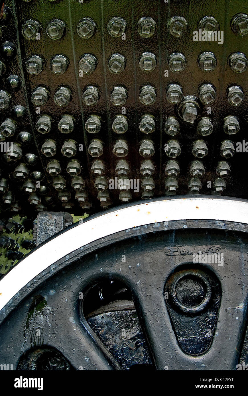 Viele Schrauben auf einer Fläche von schwarzem Eisen mit Eisenrad im Vordergrund. Stockfoto