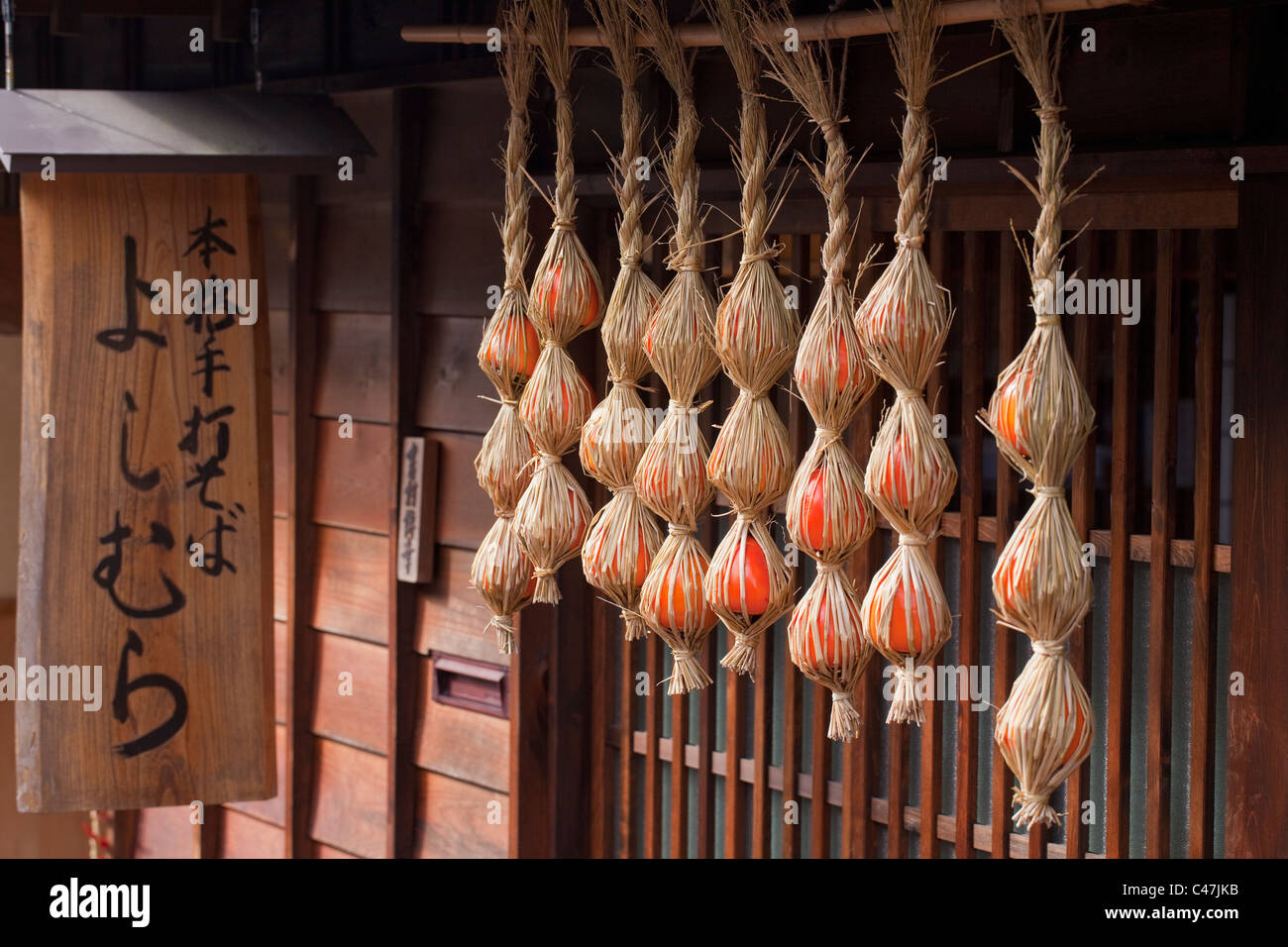 Kaki eingewickelt im Stroh hängen von Yoshimura Restaurant, Tsumango, Kiso-Tal, Nagano, Honshu, Japan. Stockfoto