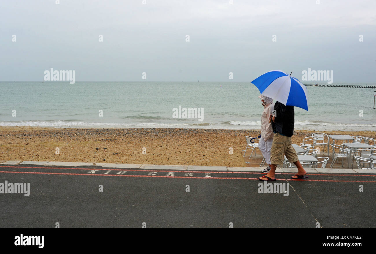 Paar mit großen hellen Schirm entlang Littlehampton direkt am Meer an einem typischen stumpfen britische Sommertag auf der South coast UK Stockfoto