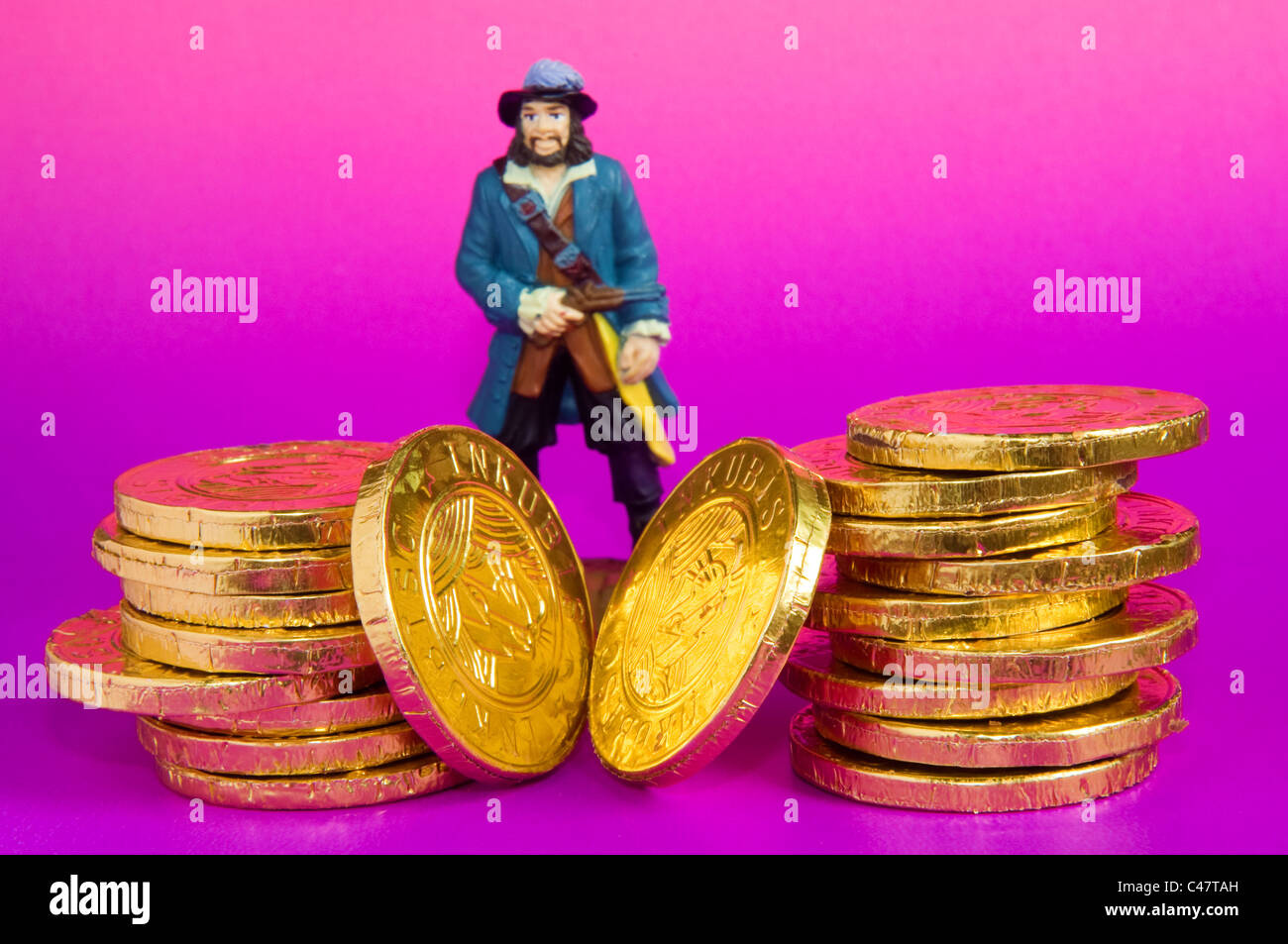 Schokoladen-goldene Münzen mit Miniatur-Kunststoff-Puppe Stockfoto