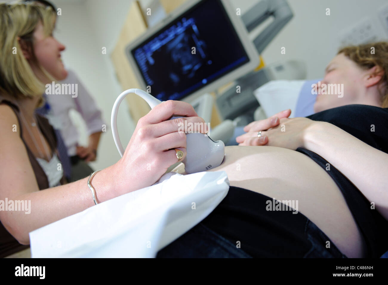 Schwangere Frau auf Beratung Patiententisch Ultraschall scan durch die Ärztin Stockfoto