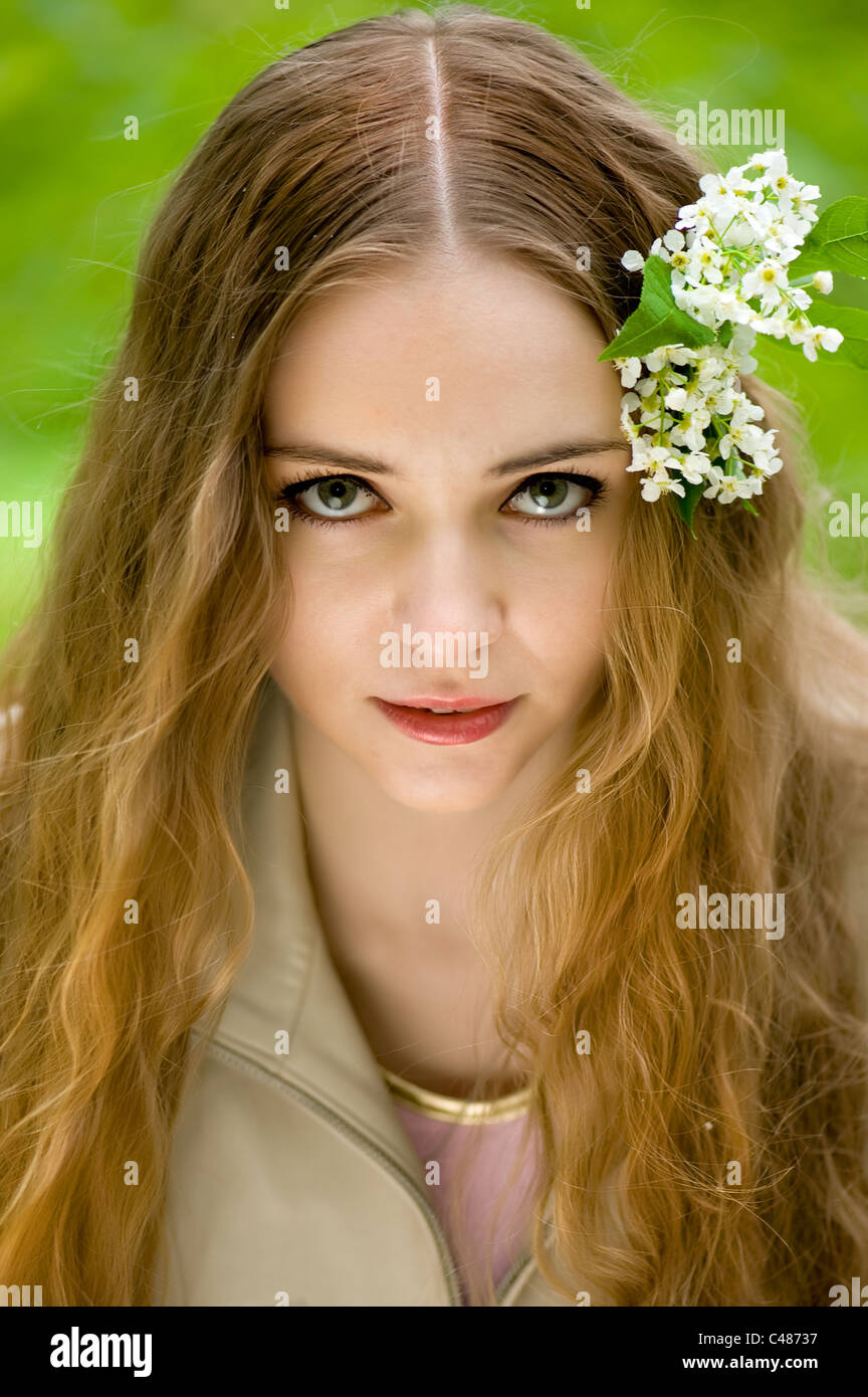 junges Mädchen mit Blumen im Haar in einen Sommerpark Stockfoto