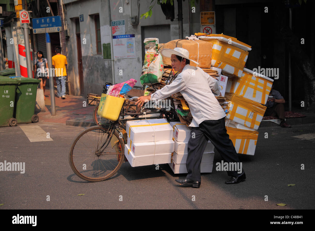 Mann schiebt überladenen Fahrrad, Guangzhou, China Stockfoto