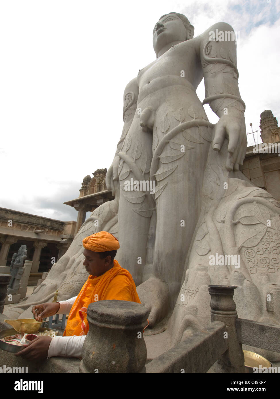 Priester unter Statue des Gomteshwara, weltweit größte Monolith-Statue, die Jain-Tempel in Shravanabelagola, Karnataka, Indien Stockfoto
