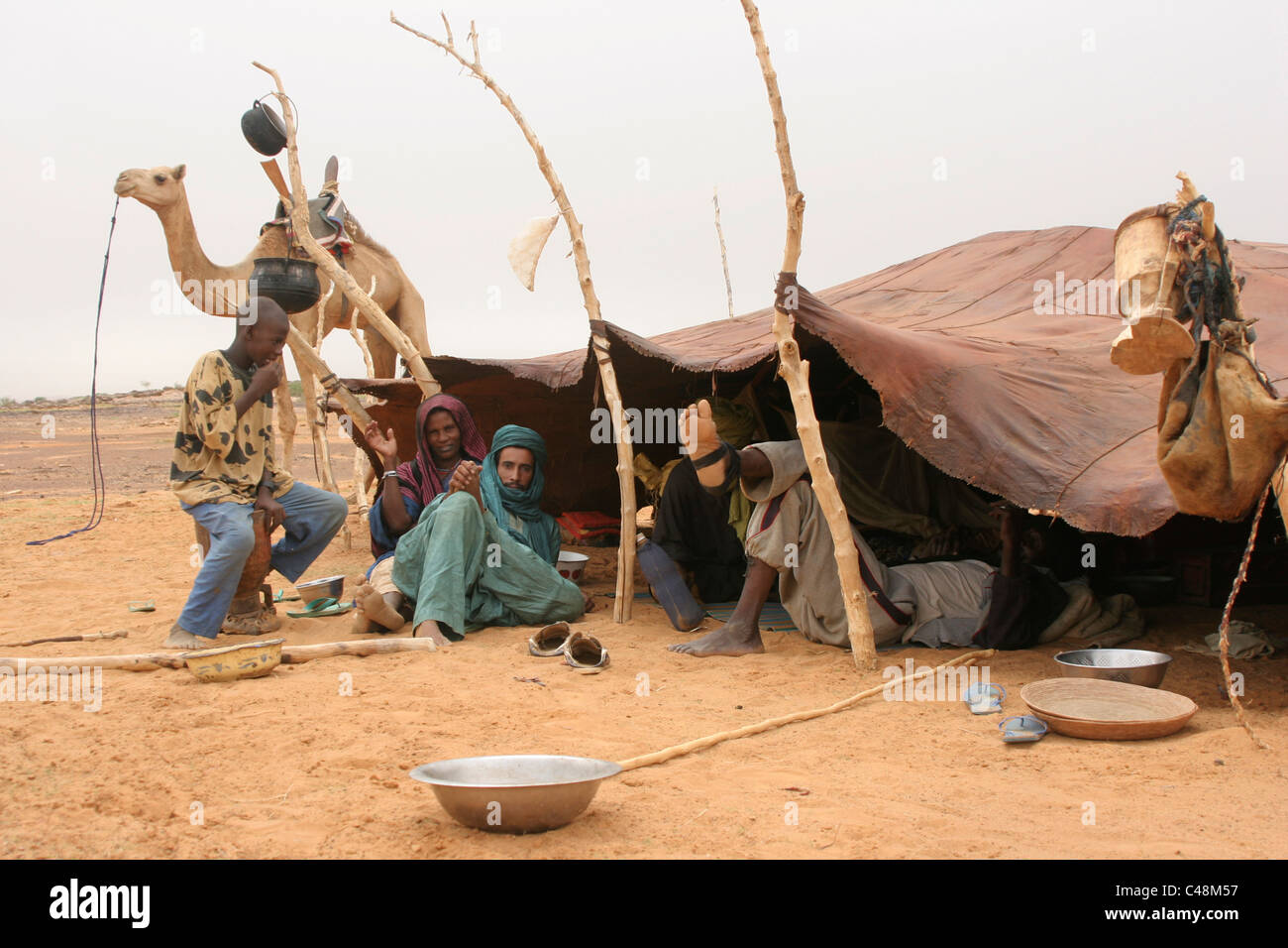 Ein afrikanische islamische Toureg Mann fesselt sein Kamel und stoppt auf einem nomadischen Lager im Sahel, Mali, Westafrika Stockfoto Ein afrikanische islamische Toureg Mann fesselt sein Kamel und stoppt auf einem nomadischen Lager im Sahel, Mali, Westafrika Stockfoto