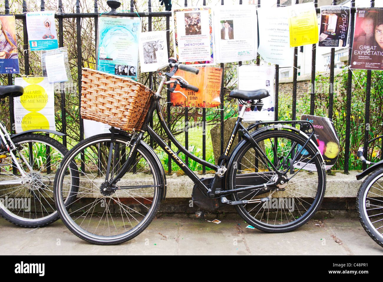 Retro-Fahrrad angekettet an Metall Zaun in einem Cambridge Stadtzentrum, umgeben von Mitteilungen und Plakate Stockfoto