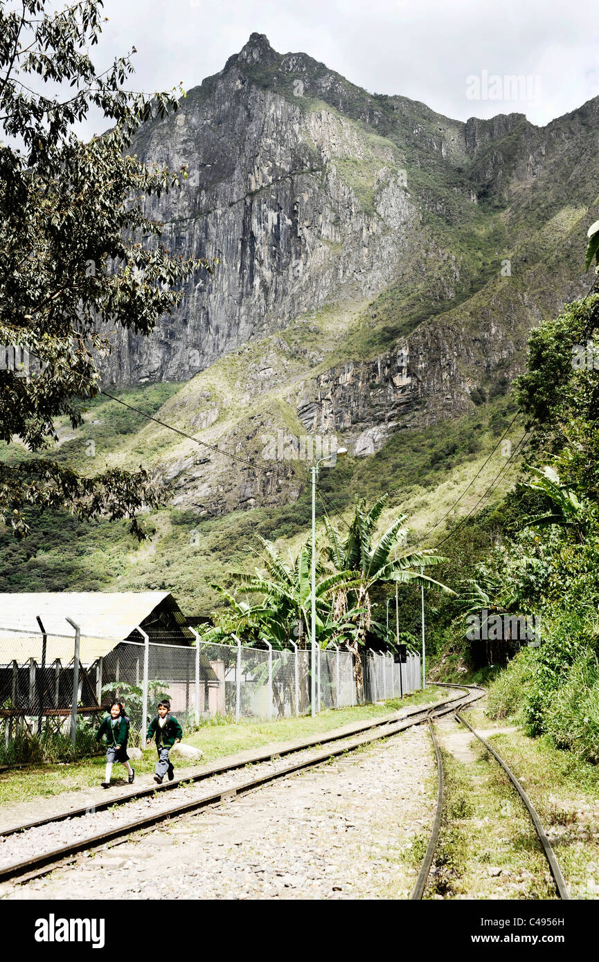 Zwei Schulkinder in grünen Uniformen Fuß entlang der Bahngleise, die aus Wasserkraft-Anlage nach Aguas Calientes, Peru führen Stockfoto