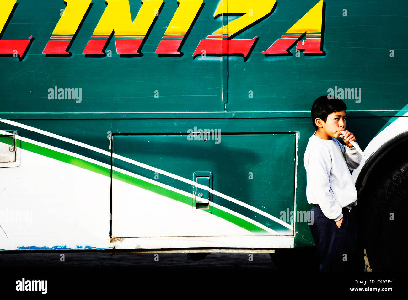 Ein Junge lehnt sich an die lokalen Busunternehmen Bus, wichtigsten Platz von Chugchilan, Quilitoa Rundwanderung, Ecuador, Südamerika. Stockfoto