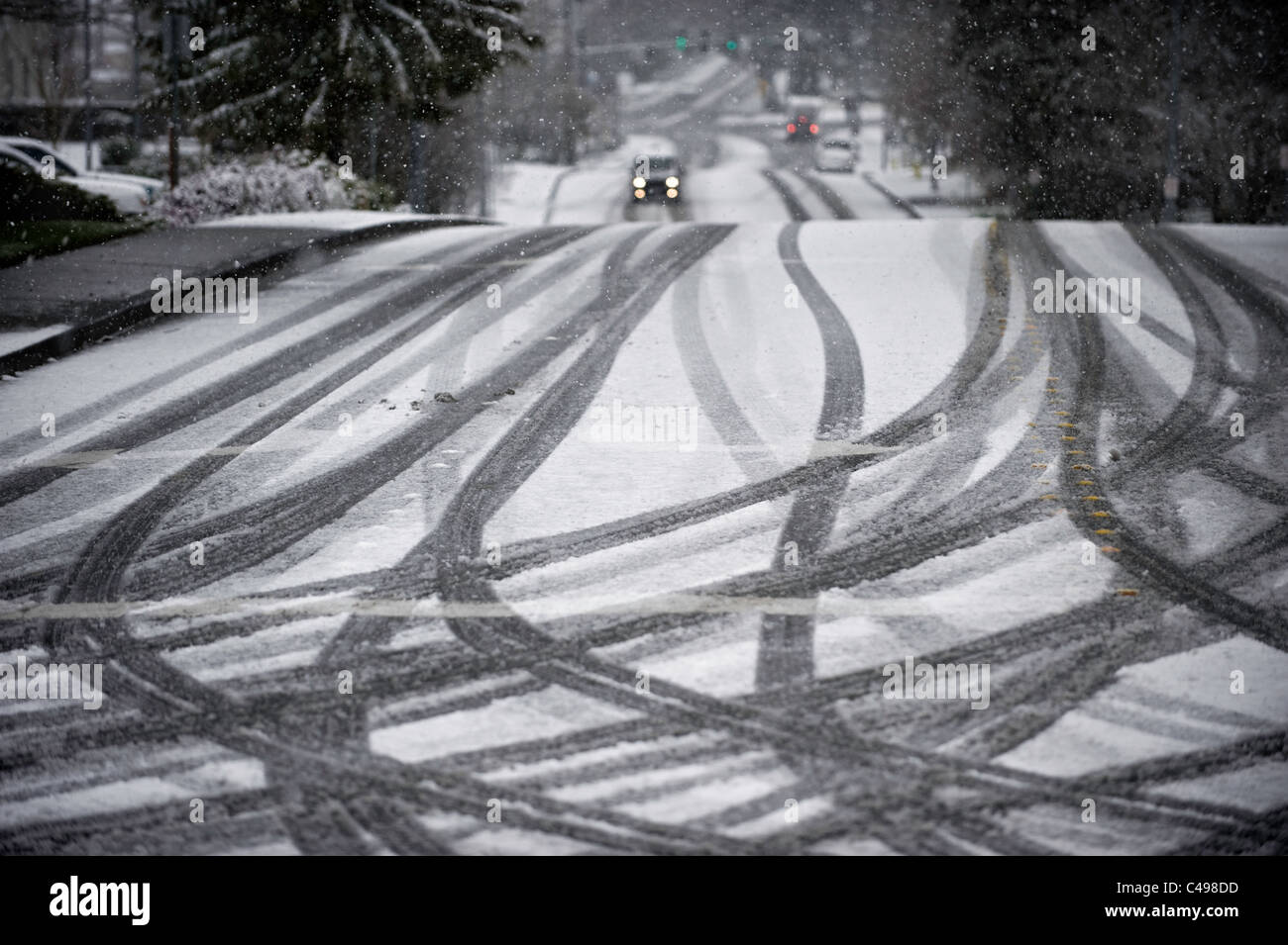 Auto auf der Straße und Reifen verfolgt während Schneesturm in Seattle, Washington, USA Stockfoto