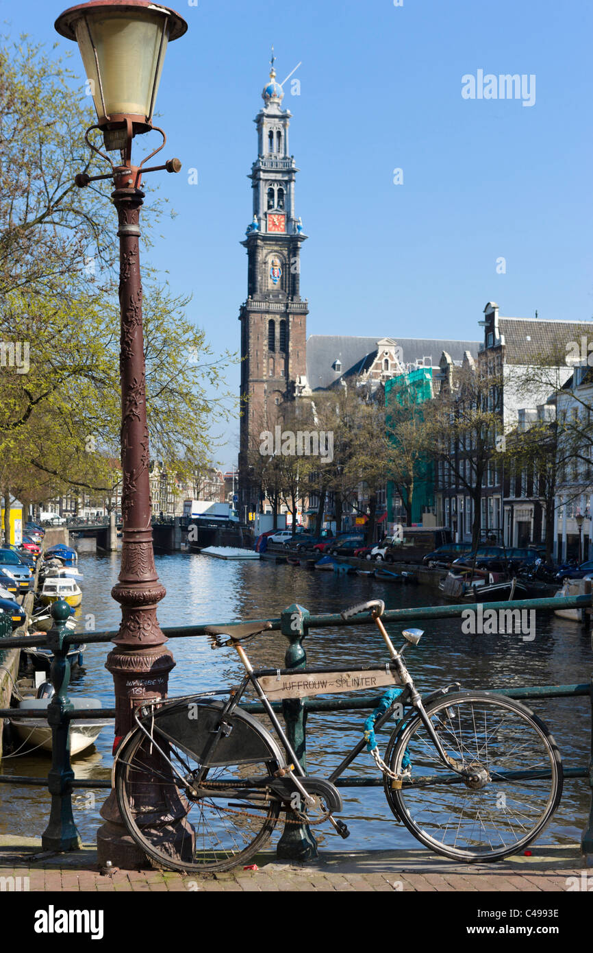 Fahrrad auf Brücke über Prinsengracht mit Turm der Westerkerk (Westertoren) hinter Grachtengordel, Amsterdam, Niederlande Stockfoto