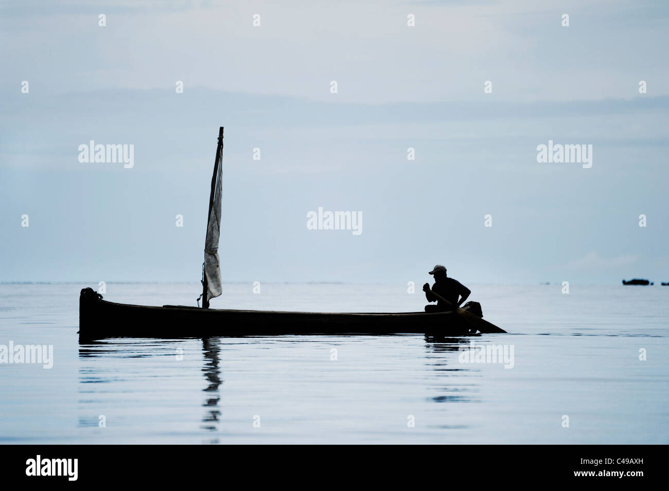 Ansicht eines indigenen Kuna Mannes sein Ruderboot vor einer Insel in San Blas Archipel der Küste von Panama in Mittelamerika Stockfoto