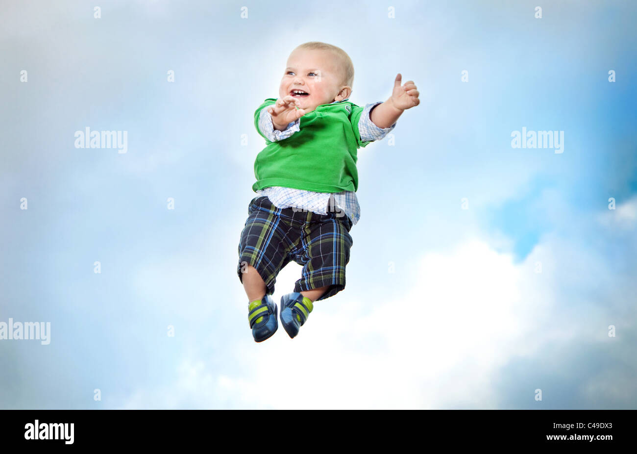 Einen kleinen Jungen in trendige Kleidung fliegen in der Luft vor einem blauen Himmel. Stockfoto