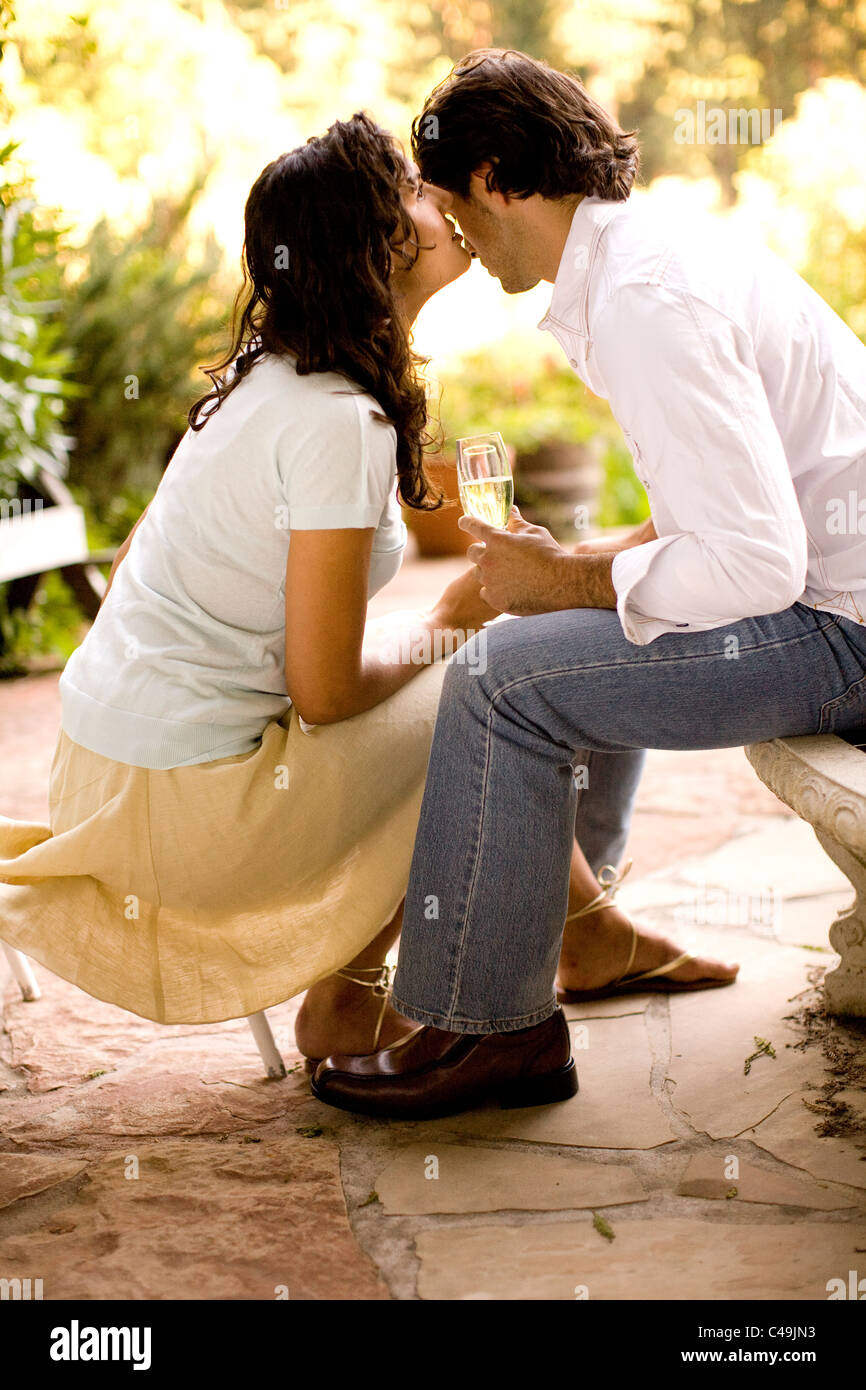 Ein Mann und eine Frau sitzen zusammen in einem Garten und Flüstern miteinander Stockfoto