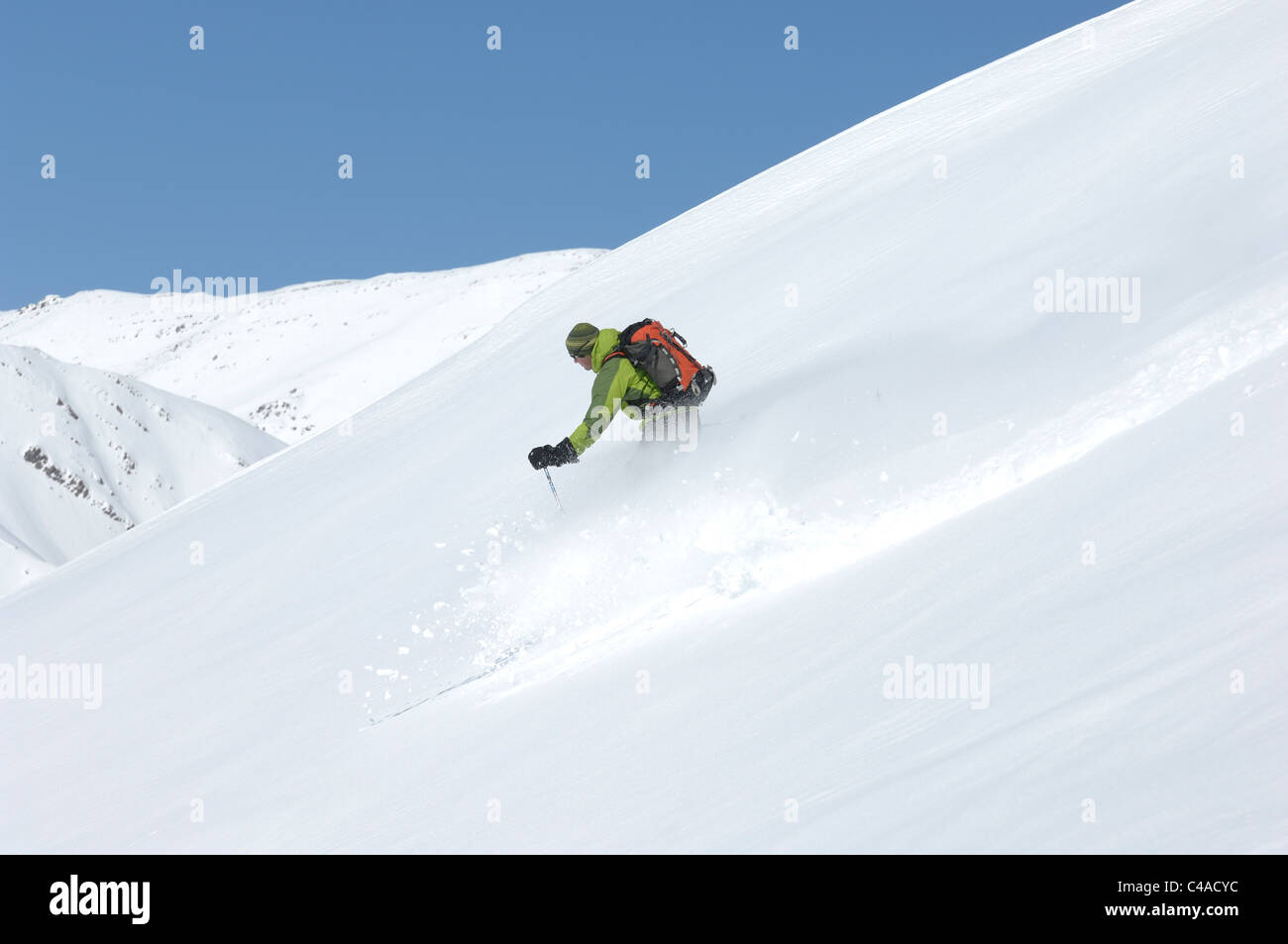 Ein Mann Ski tragen einen Rucksack abseits der Piste in frischem Schnee unter blauem Himmel in Dizin Resort Teil des Elburs-Gebirges Iran Stockfoto