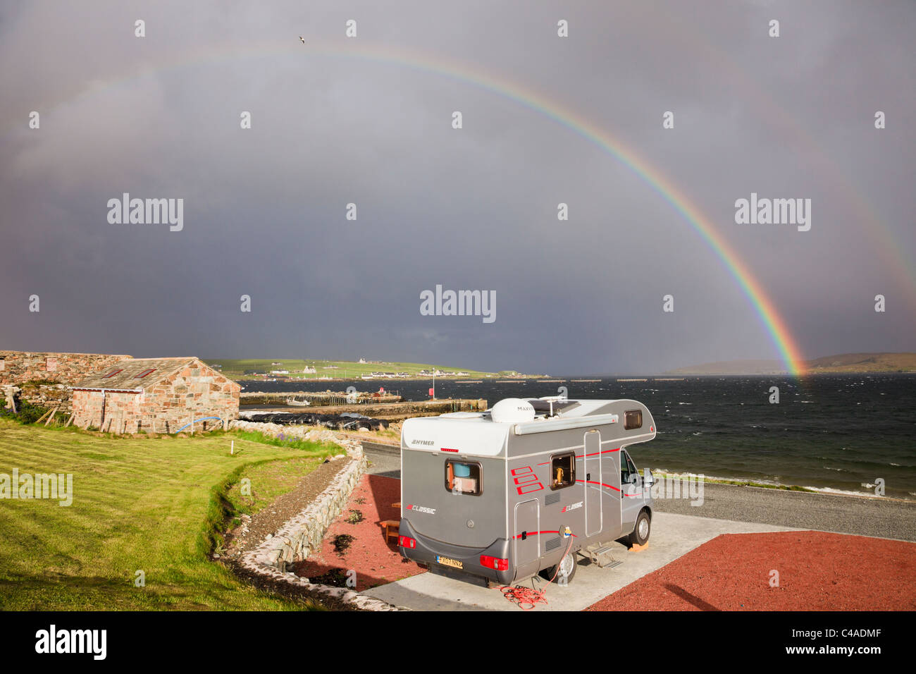 Reisemobil in Gardiesfauld Jugendherberge Campingplatz mit Rainbow und dunkle Wolken im Sommer. Uyeasound, Insel Unst, Shetlandinseln, Schottland, Großbritannien. Stockfoto