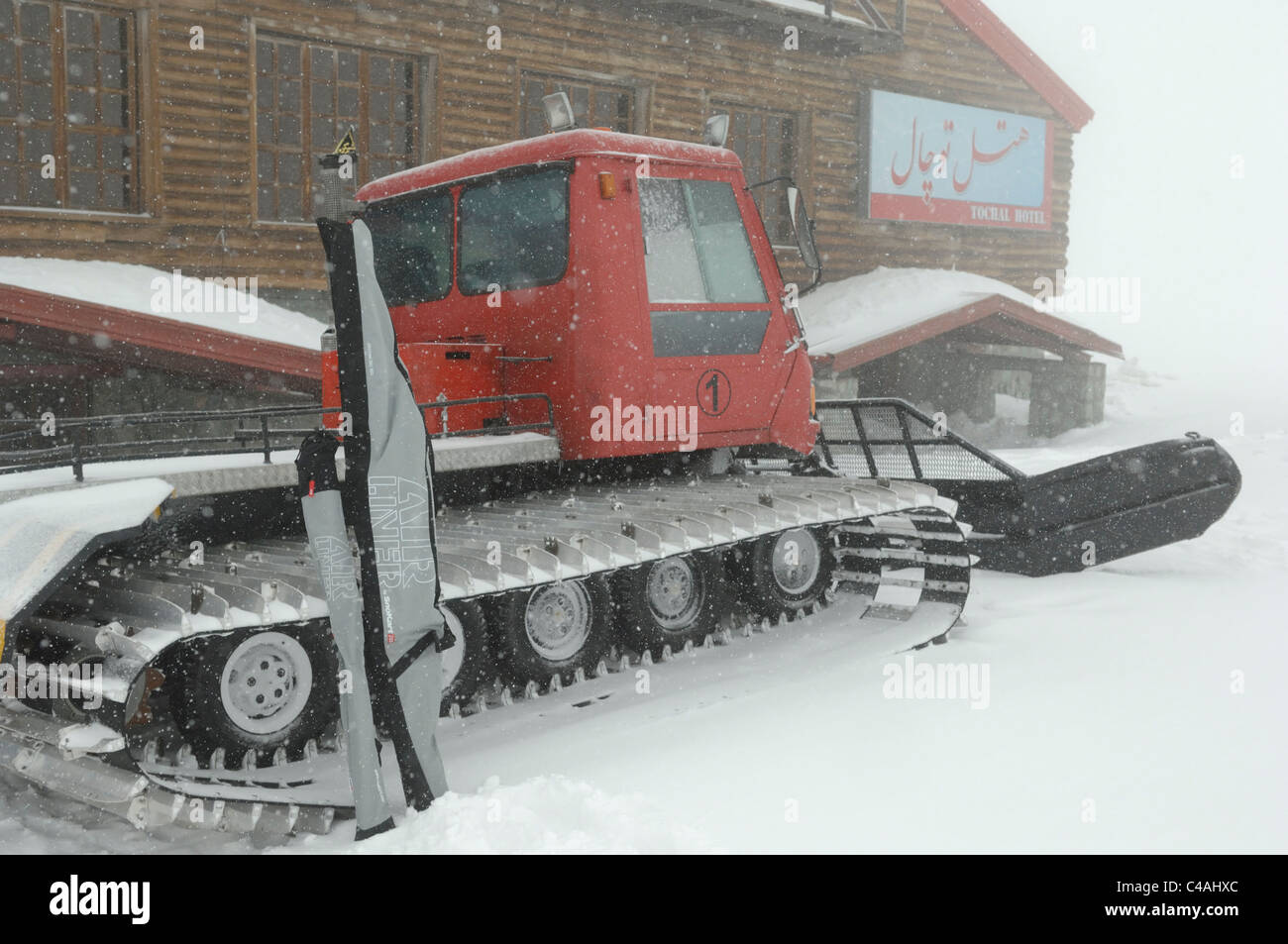 Ski stützte sich gegen eine Pistenraupe Tochal Hotel im Skigebiet Tochal über Teheran im Iran während starker Schneefall Stockfoto