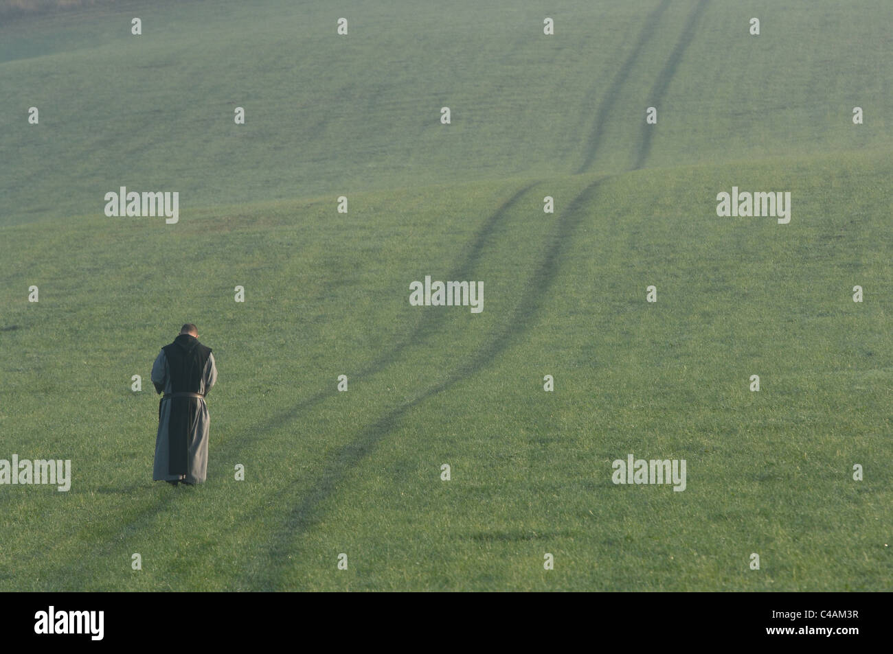 Ein Mönch Geht Auf Einer Tracktorspur in Einer Wiese (Nahe Kloster Mariawald). Stockfoto