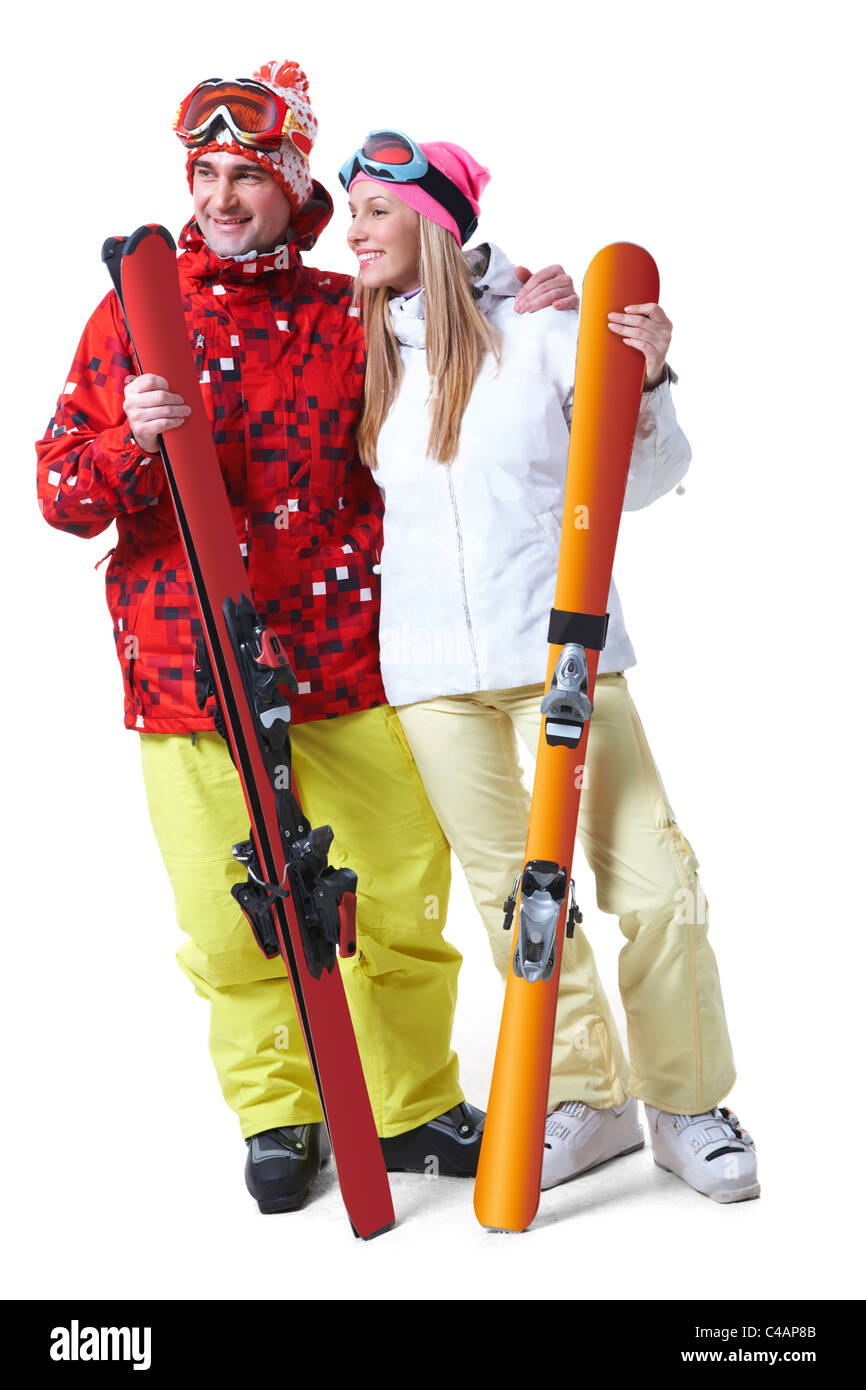 Porträt des glücklichen Paares mit Skiern in Händen, die auf der Suche zur Seite mit einem Lächeln Stockfoto