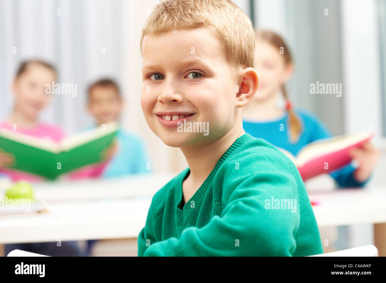 Süße junge Blick in die Kamera auf Grund seiner Klassenkameraden Stockfoto