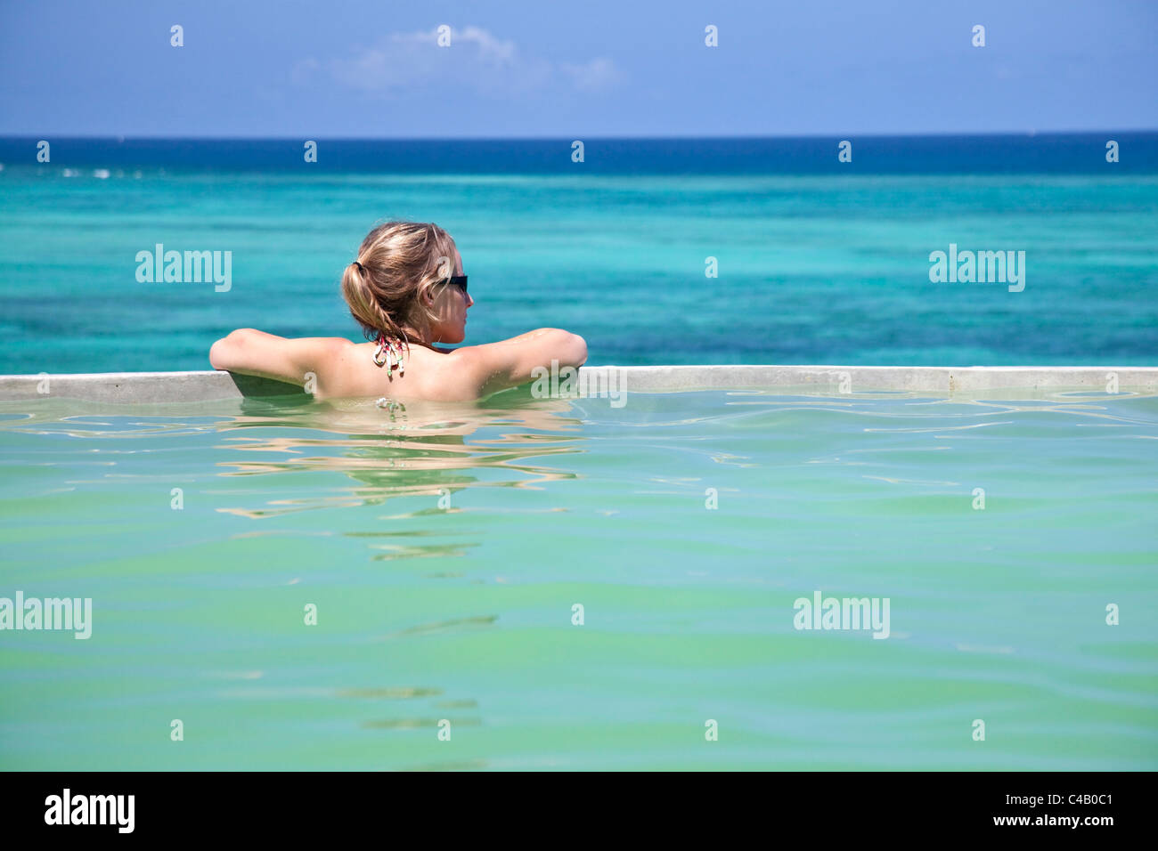 Sansibar, Shooting Star Lodge. Ein Gast entspannt im Infinity-Pool mit Blick auf Sansibars Ostküste. MR. Stockfoto