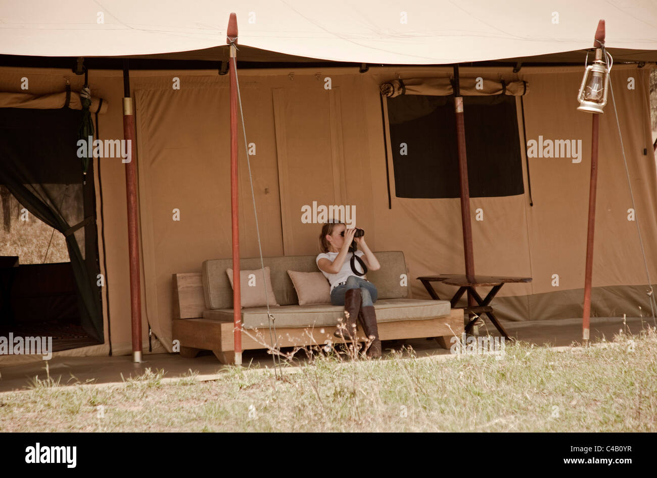Tansania, Serengeti. Ein Gast blickt auf den Ebenen bequem von ihrem Zelt am Lemala Ewanjan. MR. Stockfoto