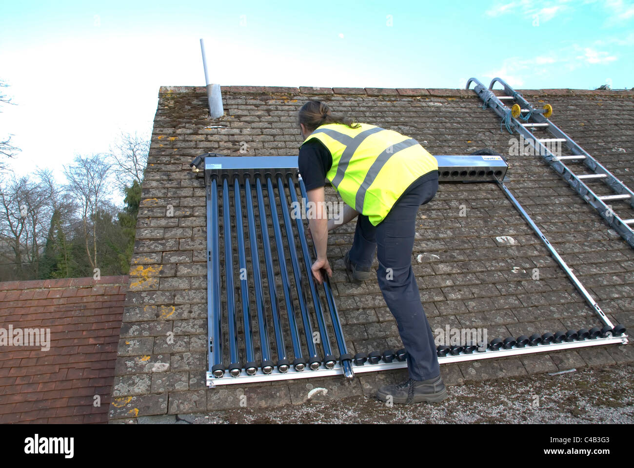 Ingenieure, die Installation solar thermische evakuierten Röhre Array auf dem Dach eines inländischen Hauses Erneuerbare Wärme und Warmwasser Stockfoto