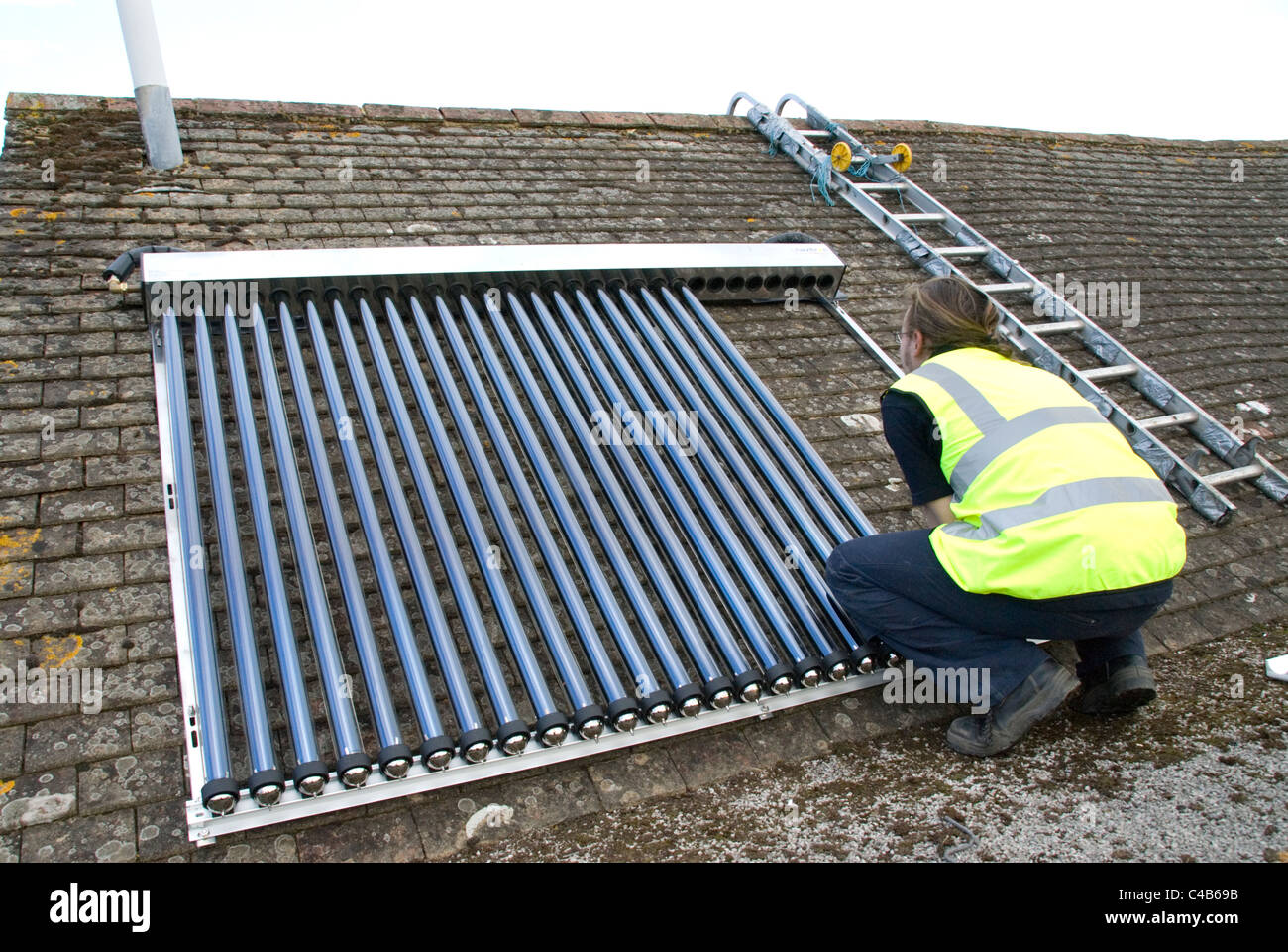 Ingenieure, die Installation solar thermische evakuierten Röhre Array auf dem Dach eines inländischen Hauses Erneuerbare Wärme und Warmwasser Stockfoto
