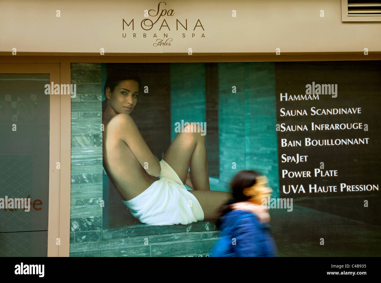 Arles; Bouches du Rhone, Frankreich; Eine junge Frau zu Fuß vor einer Spa-Anzeige. MR. Stockfoto