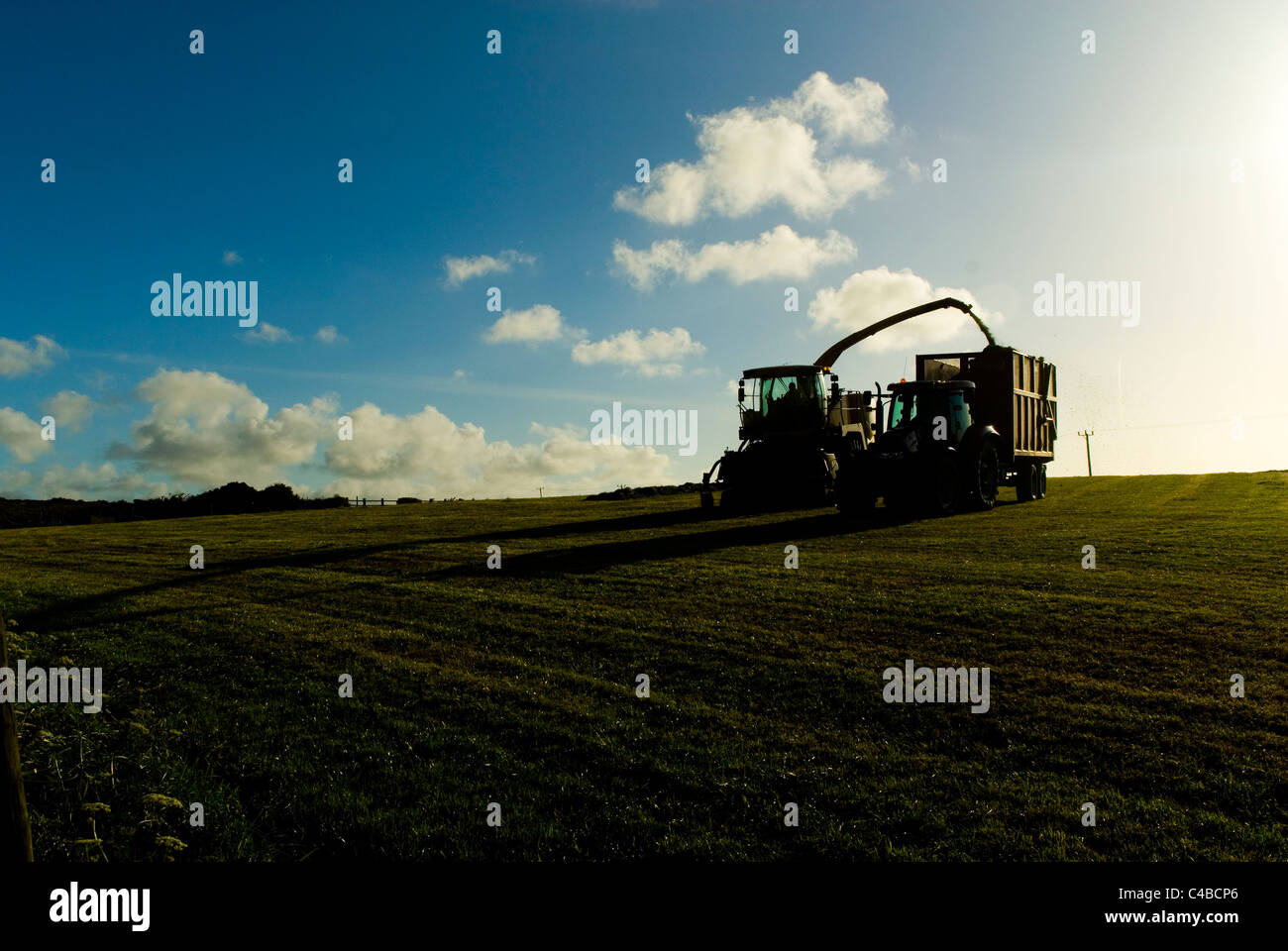 Landwirtschaftliche Fahrzeuge arbeiten im Abendlicht, Heu, Cornwall England UK zu sammeln Stockfoto