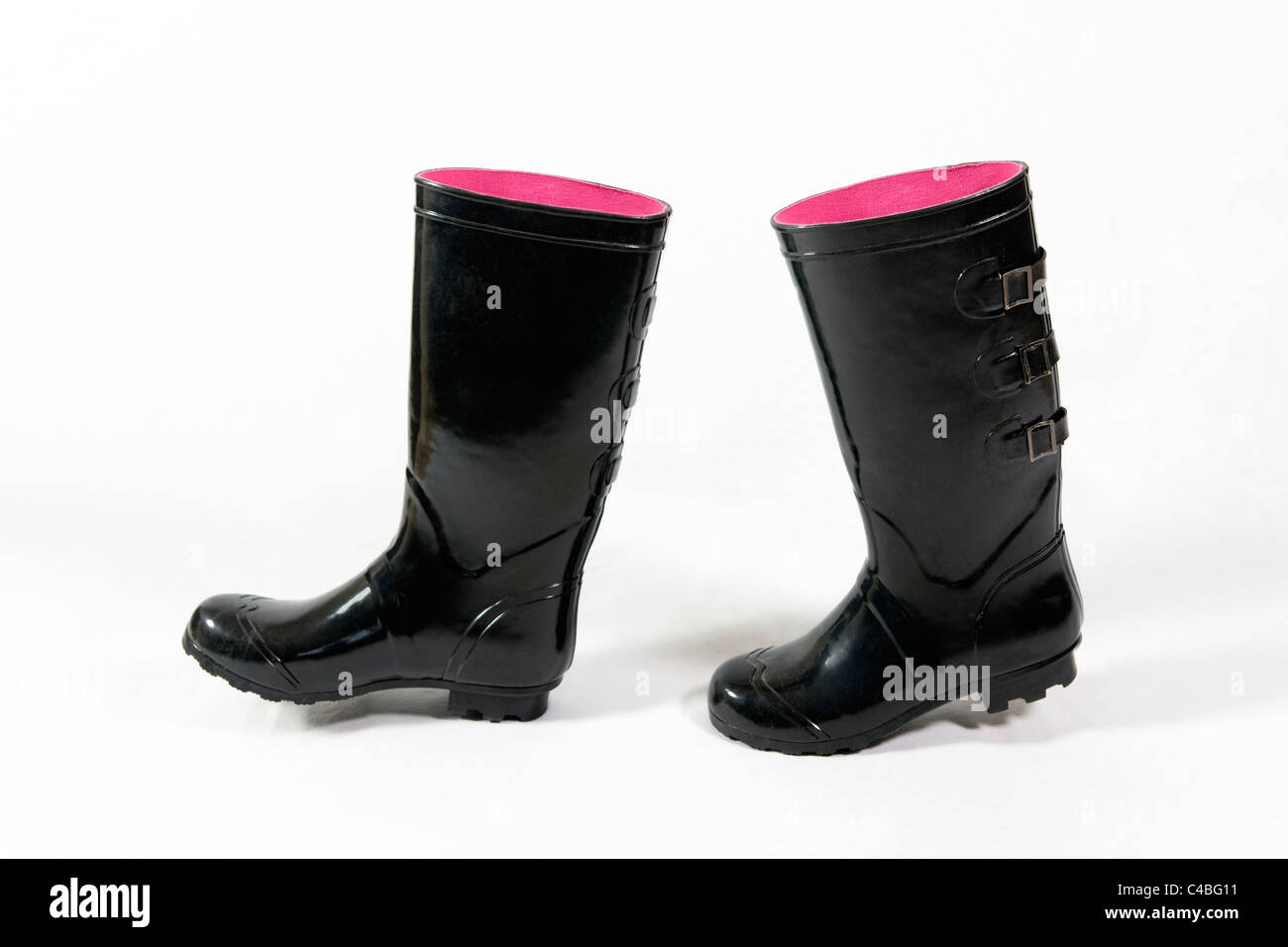 Ein paar schwarze Gummistiefel oder Wellington Stiefel mit rosa innen genommen vor einem weißen Hintergrund platziert, als ob sie Fuß sind Stockfoto