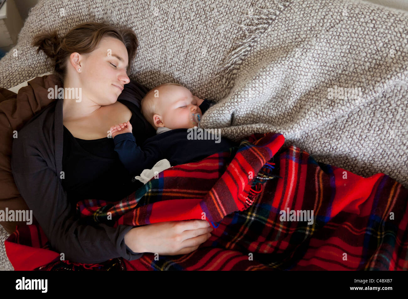 Mutter schläft mit ihrem Baby (5 Monate alt) auf dem Sofa. Stockfoto
